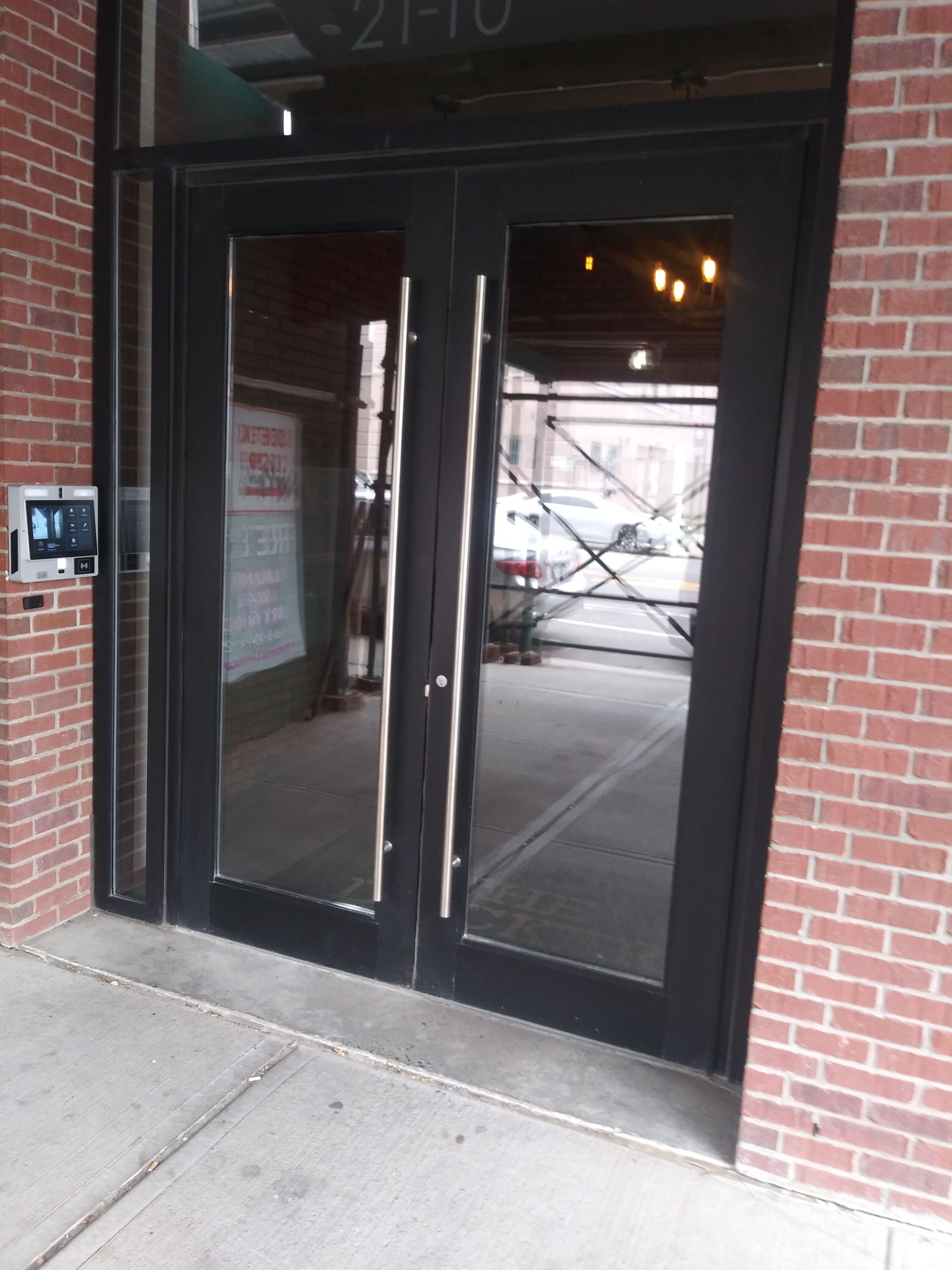Glass storefront entrance with double black doors set in a red brick building.