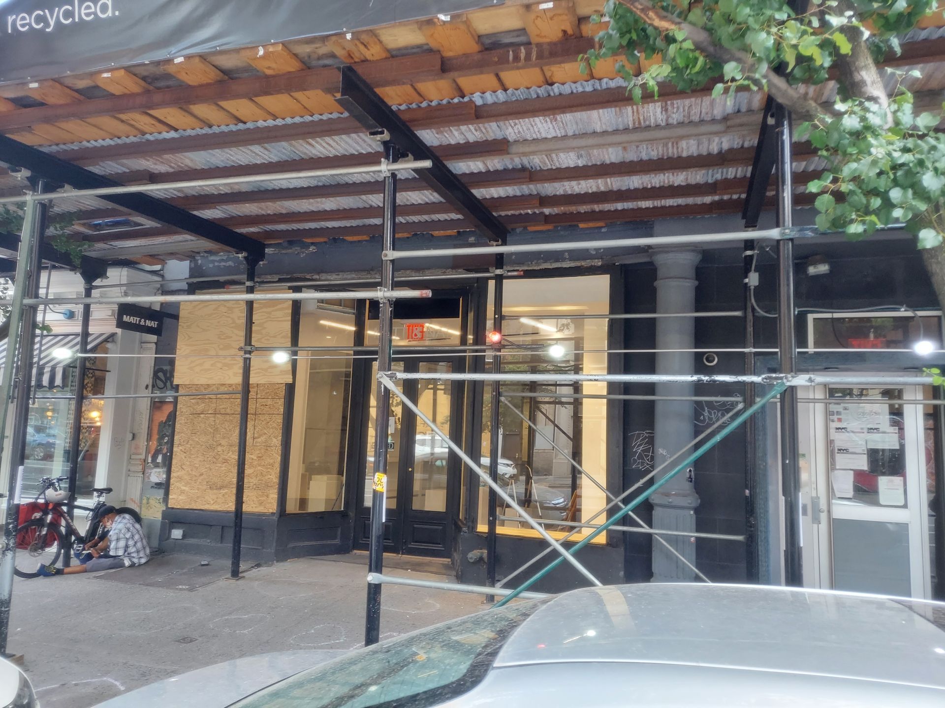Storefront under construction with scaffolding, metal awning, and bicycles parked outside