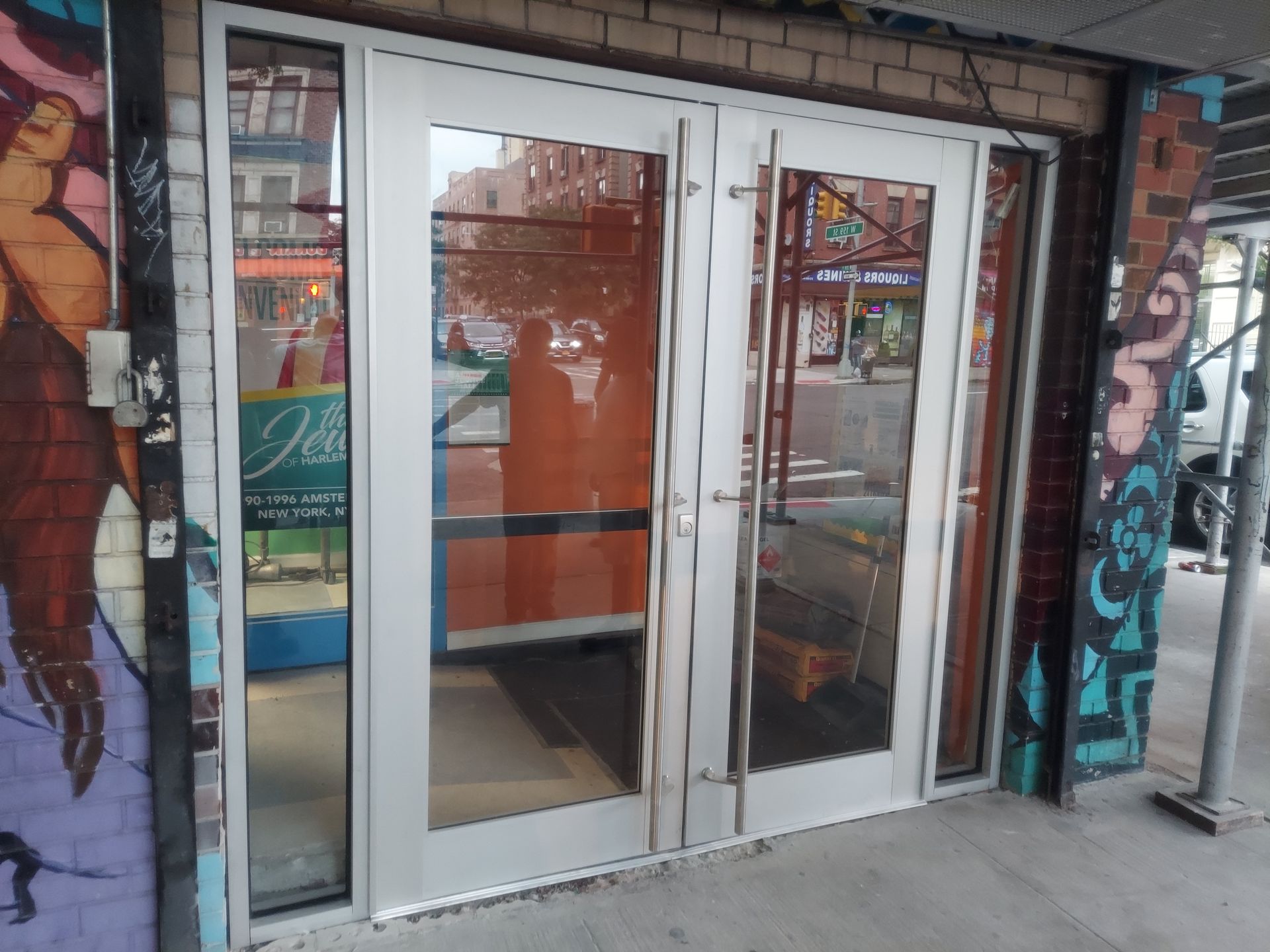 Glass storefront double doors framed by brick, with posters and reflections visible in the windows