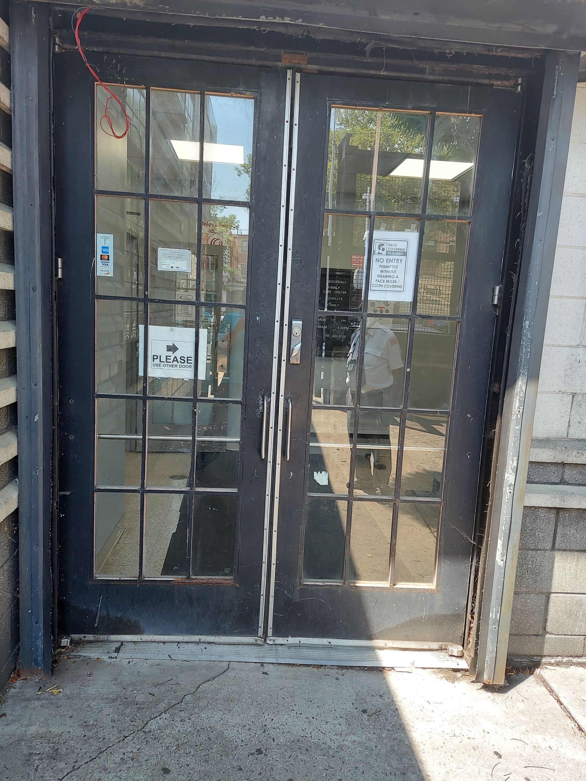 Glass double doors at a building entrance with posted notices and a concrete step.