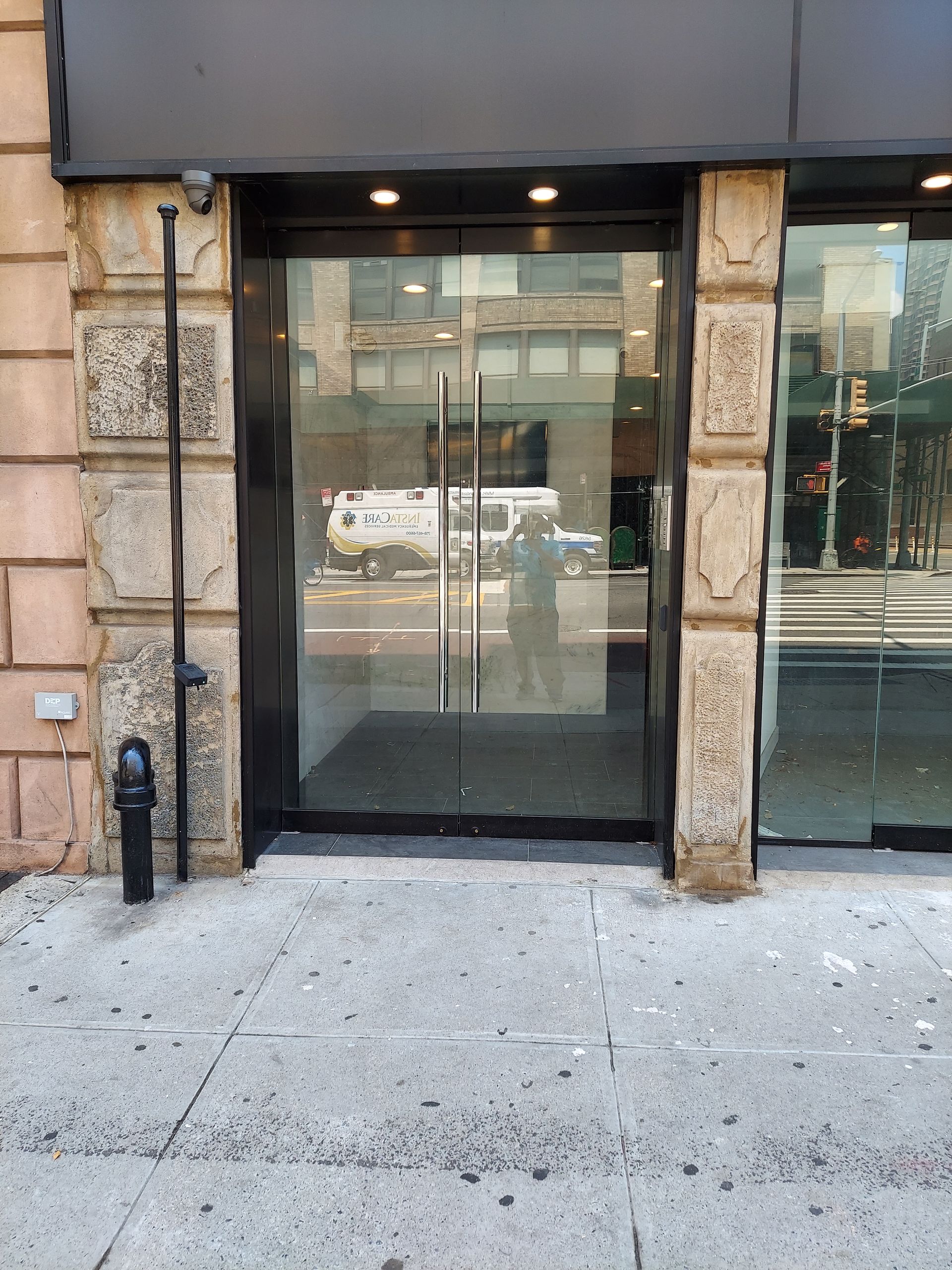 Building entrance with glass double doors and stone facade on a city sidewalk