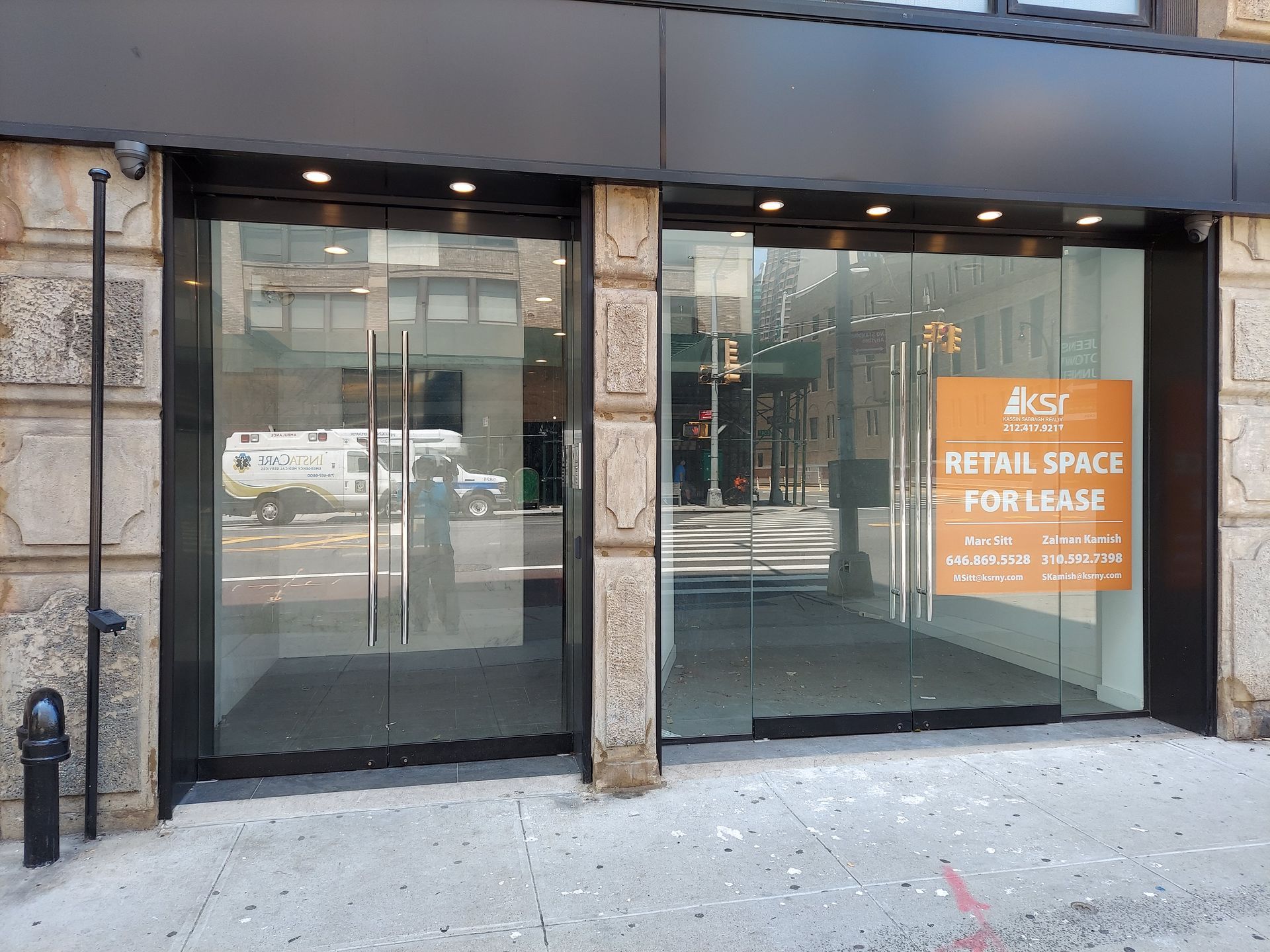 Empty storefront with glass doors and windows, showing a red 