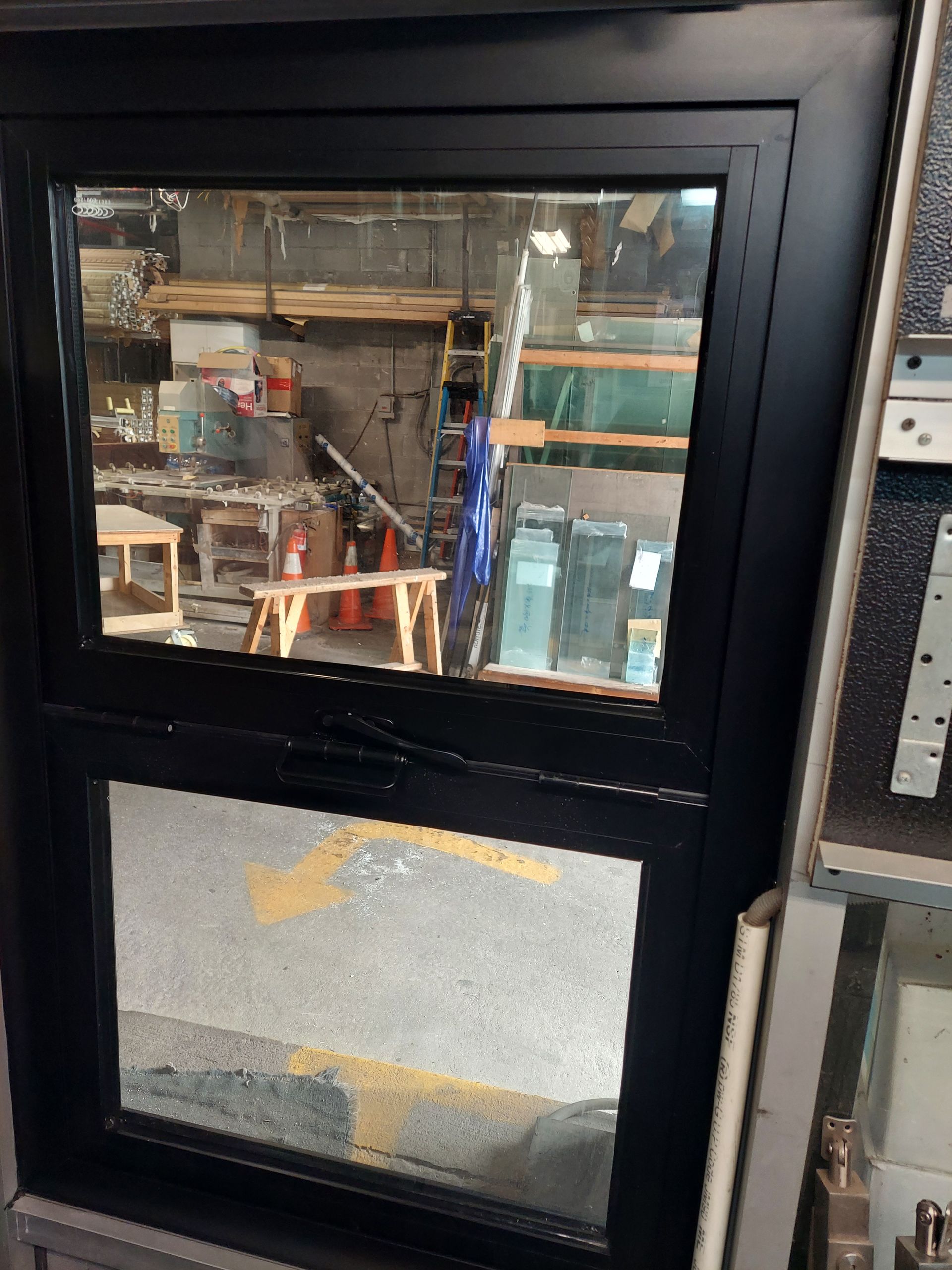 Black-framed glass door with workshop equipment visible behind it and a lower frosted panel.