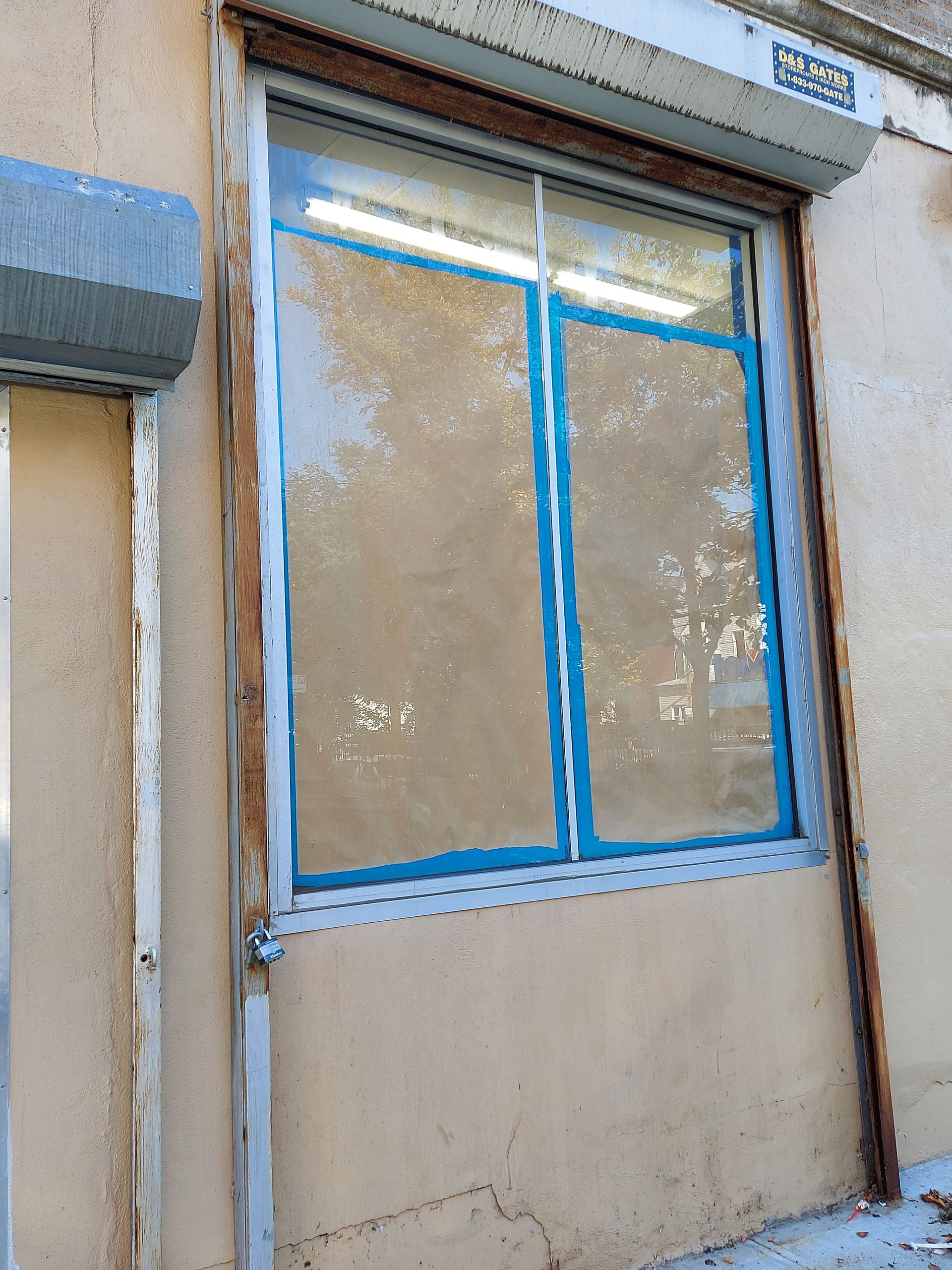 Blue-framed window on a beige wall, covered with blue painter’s tape.
