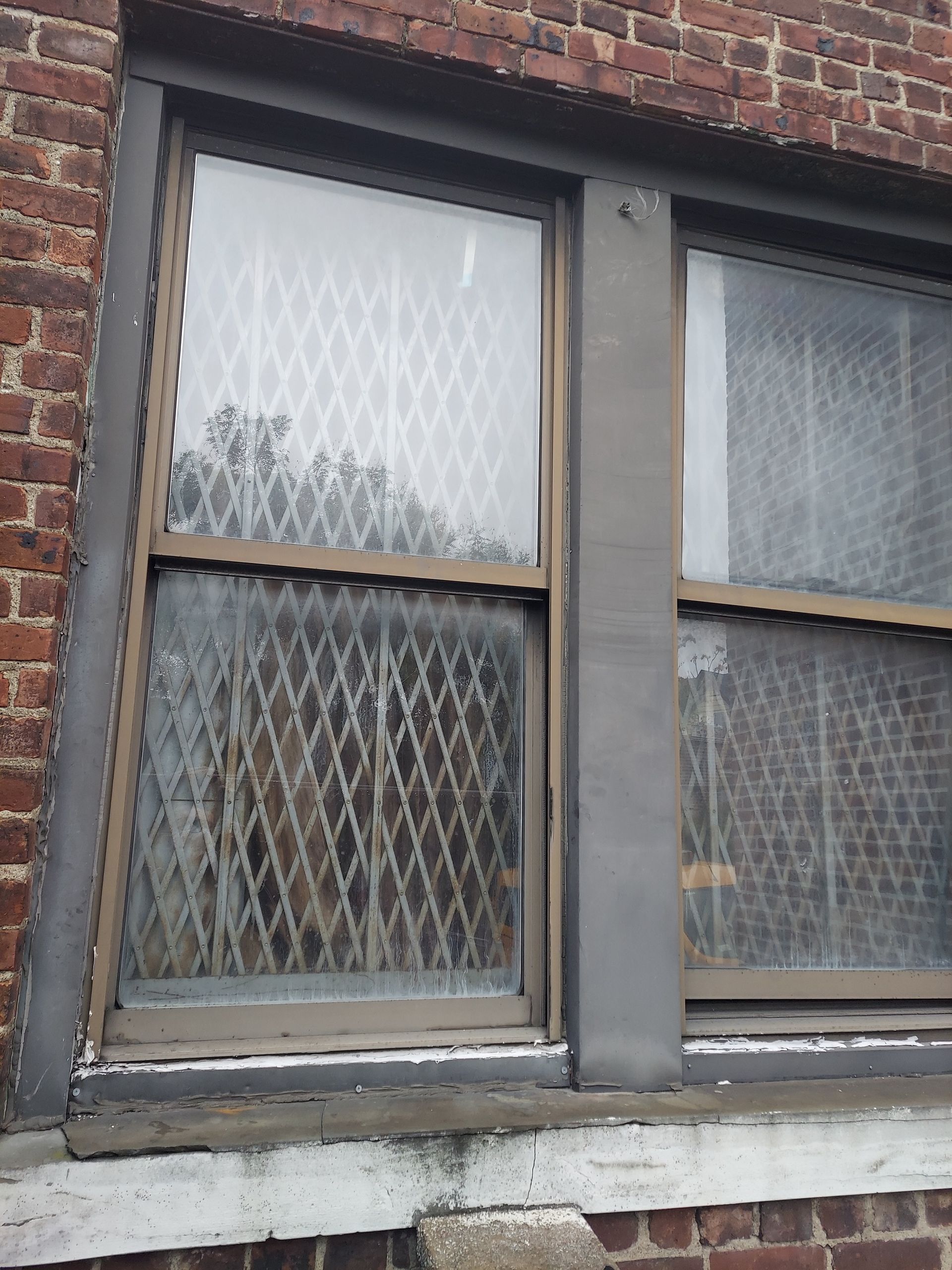 Two old windows with diamond-patterned frosted glass in a brick wall facade