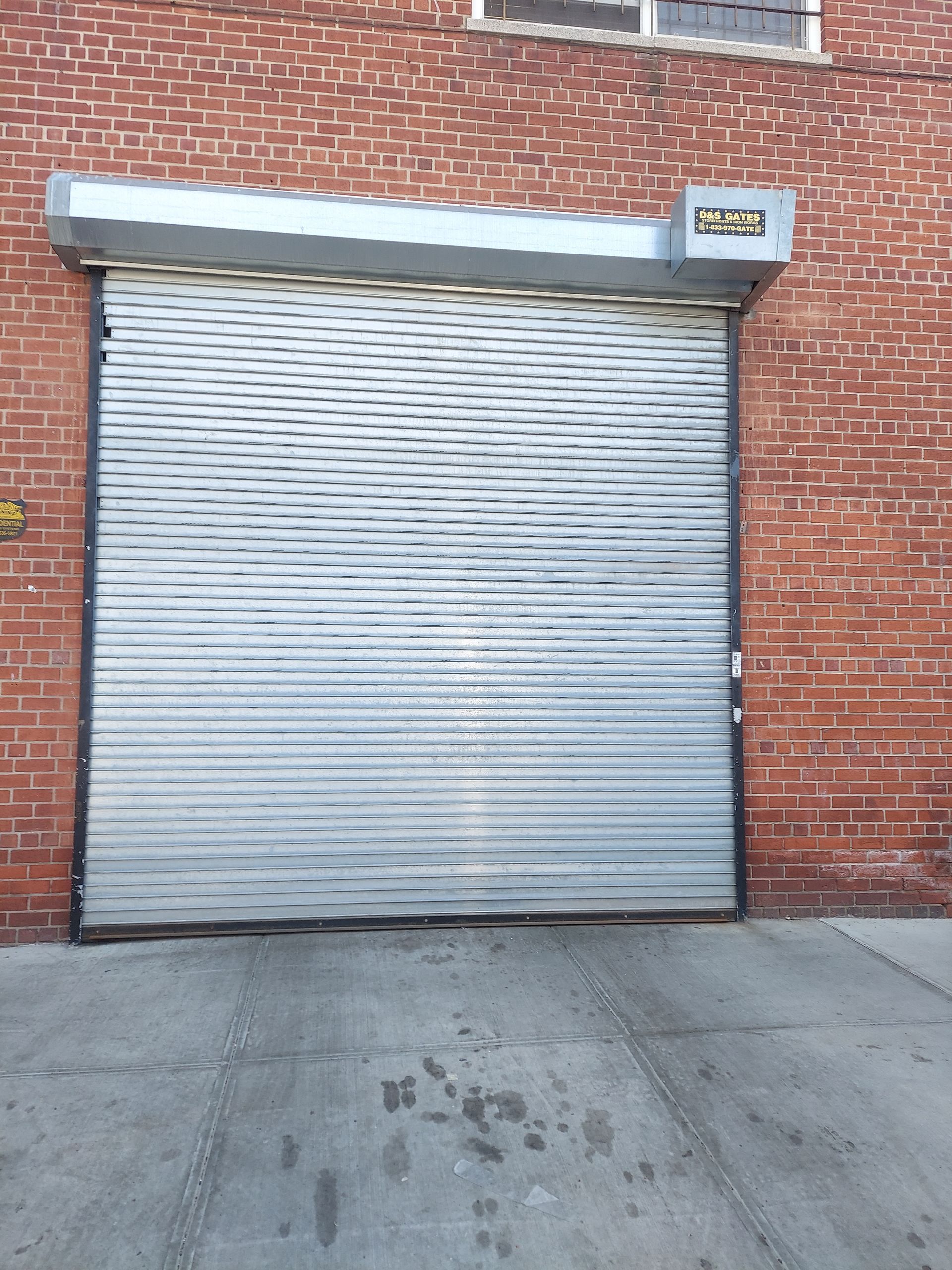 Closed silver roll-up door in a red brick building exterior.