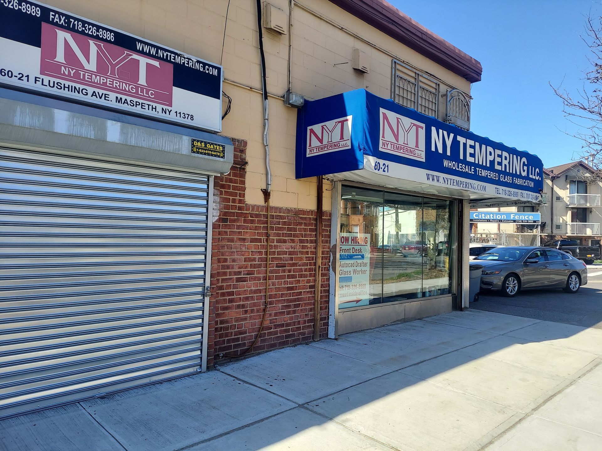 NY Towing storefront with blue awning, metal shutters, and parked car on a sunny street
