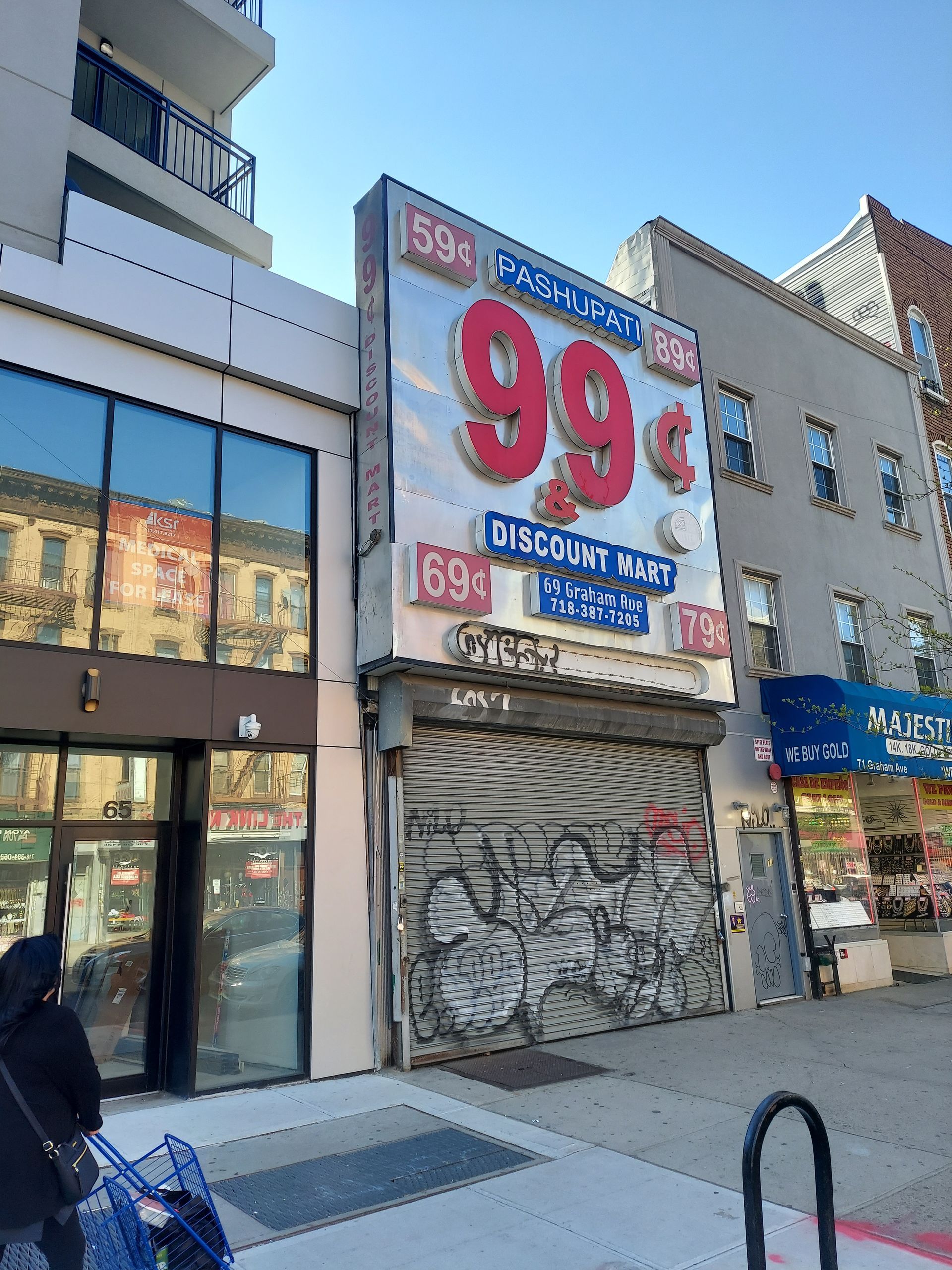 Shuttered storefront with a large “99” sign and discount ads on a city street