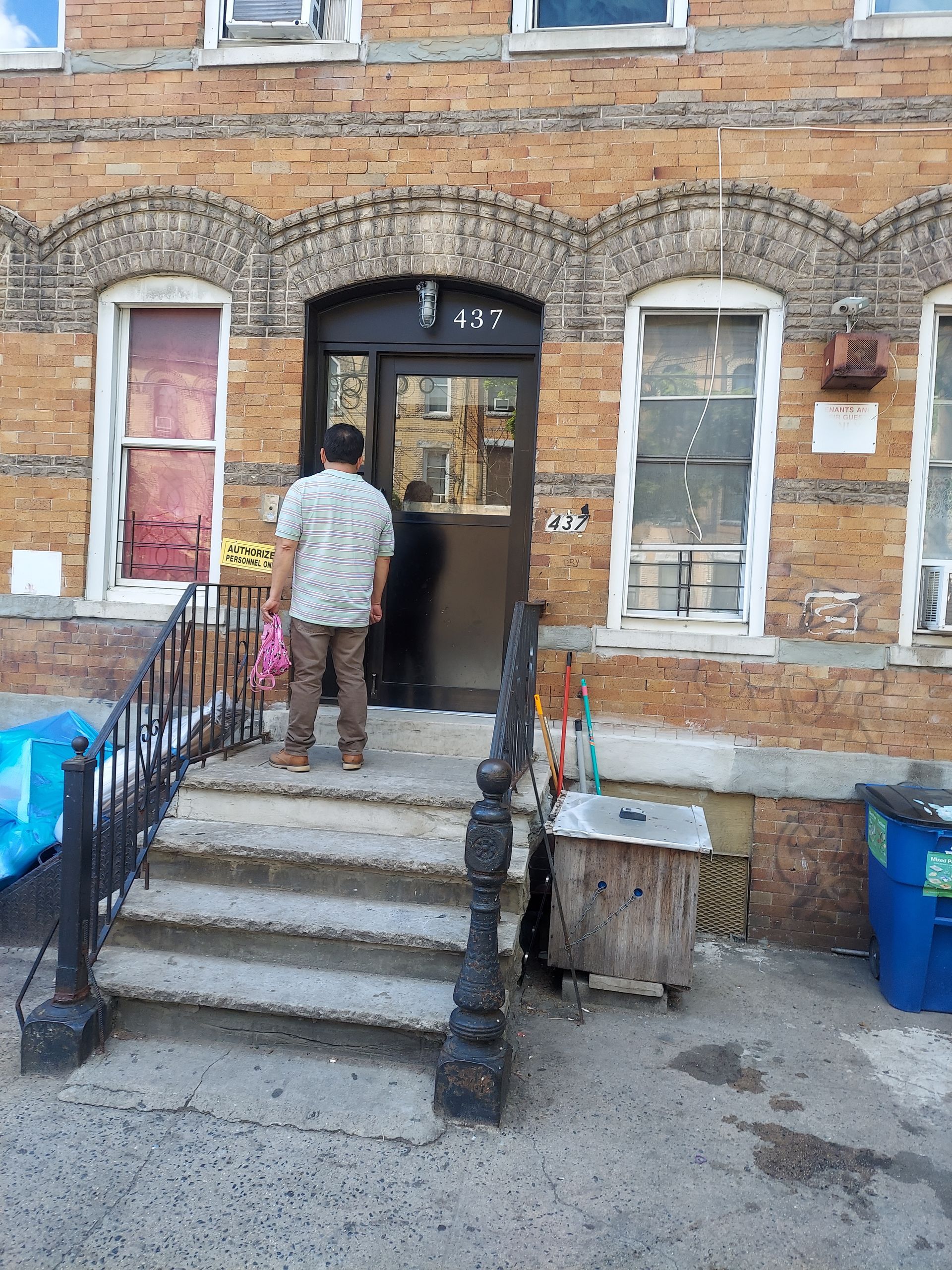 Person entering a brick apartment building up concrete steps