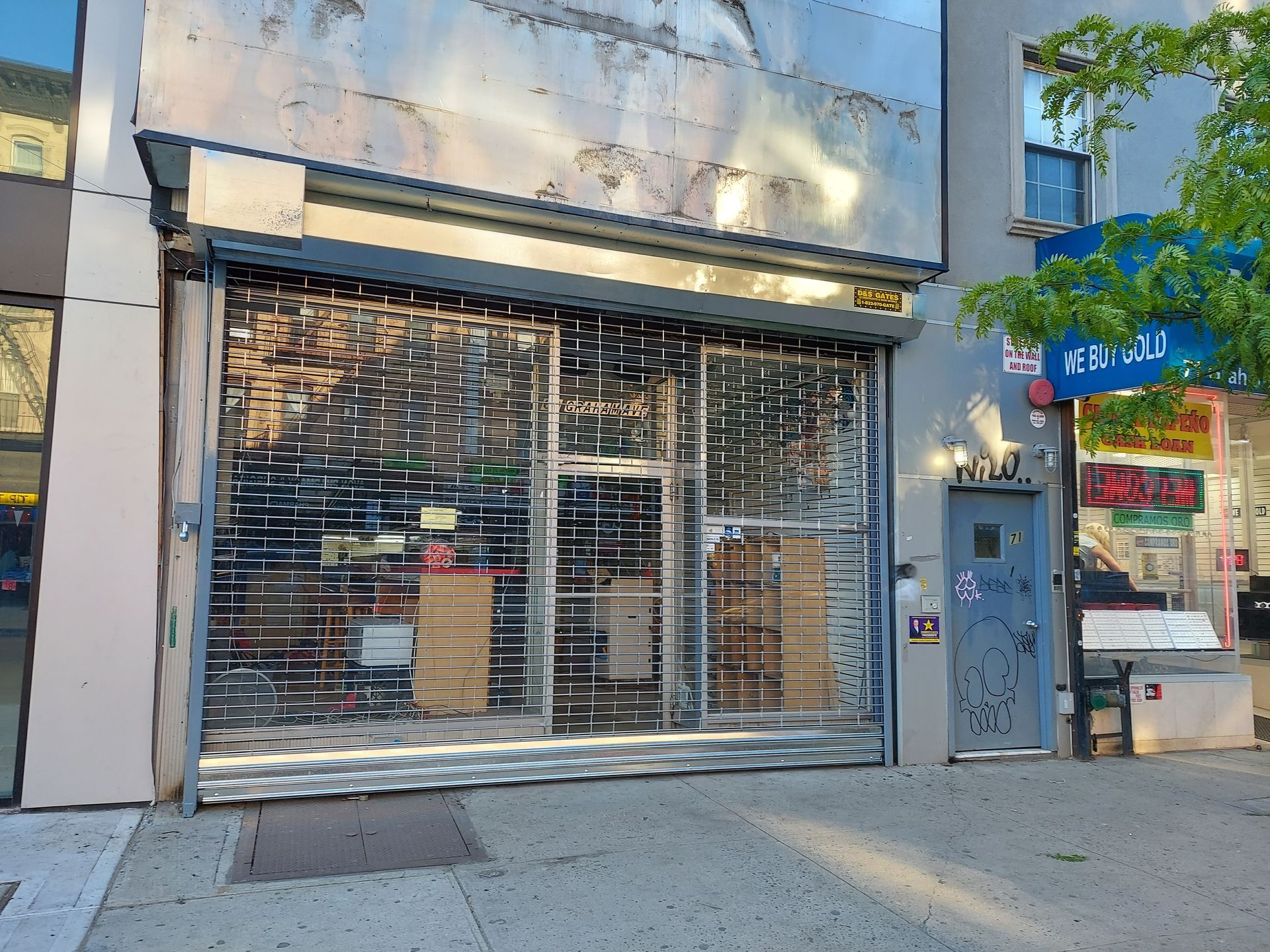 Closed storefront with metal security gate on a sunny street corner