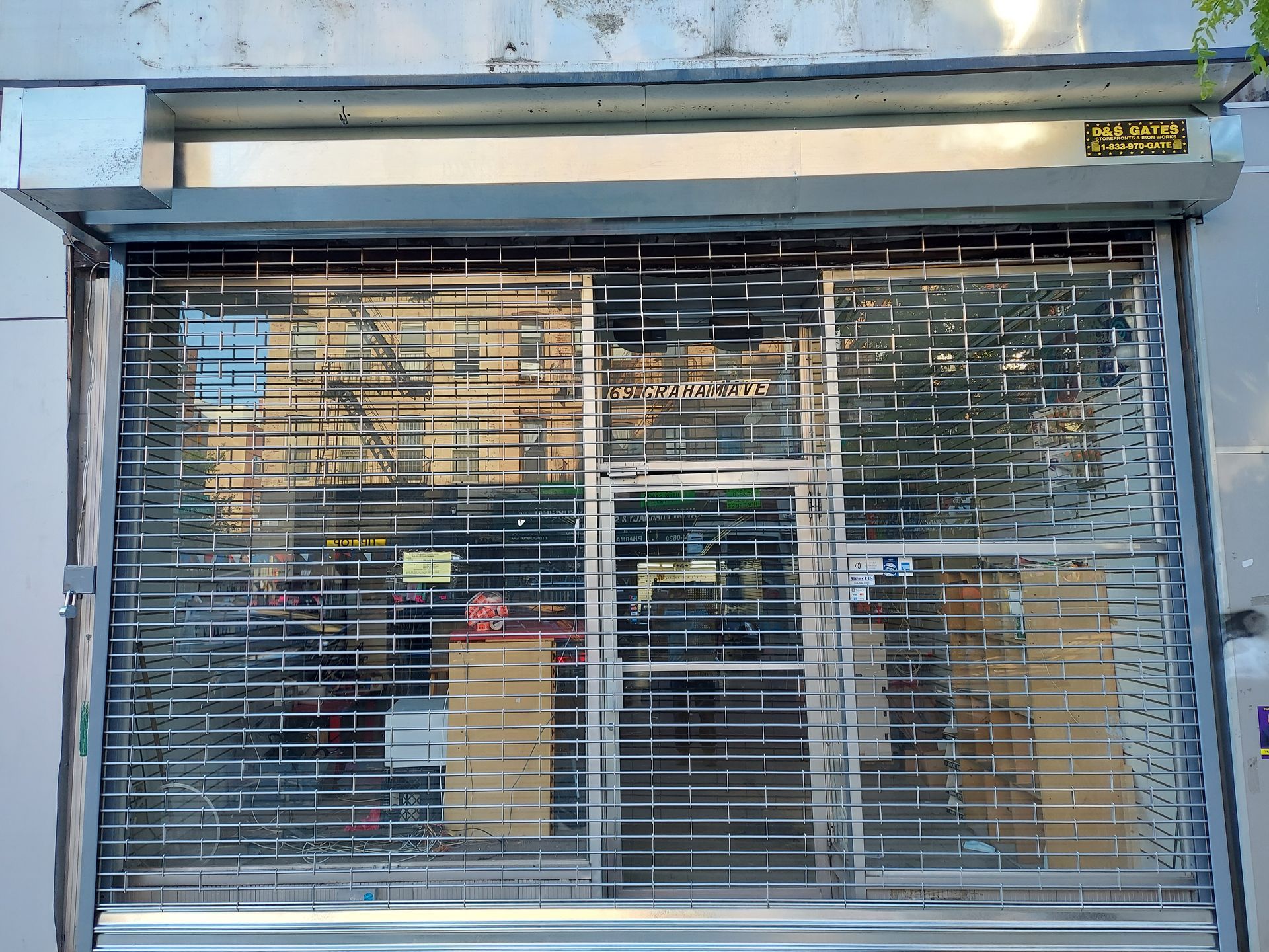 Closed storefront with metal security shutters and glass windows reflecting the street