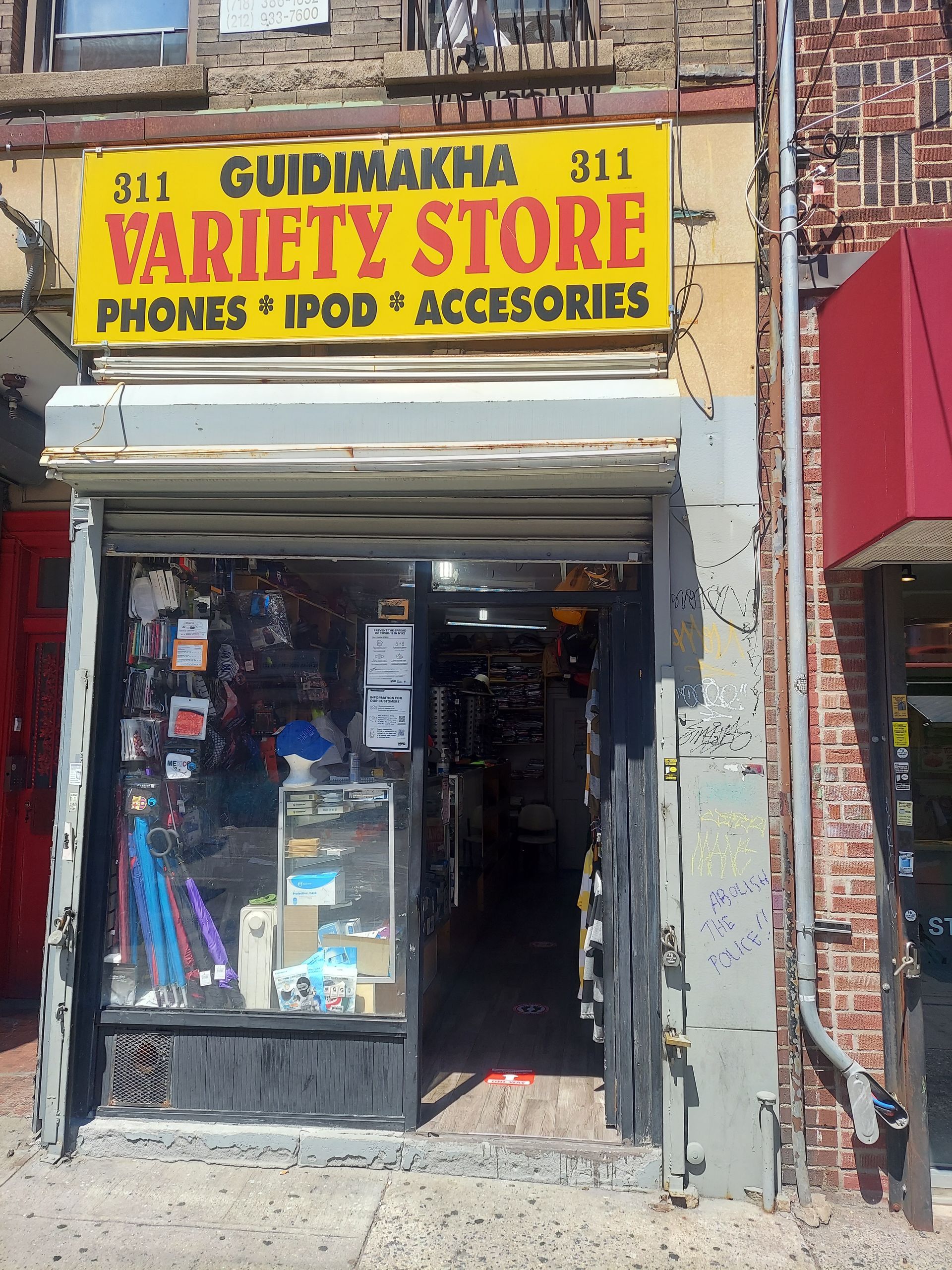 Storefront for “Ol’ Grandma Sit Variety Store,” with a yellow sign and phone accessories display.