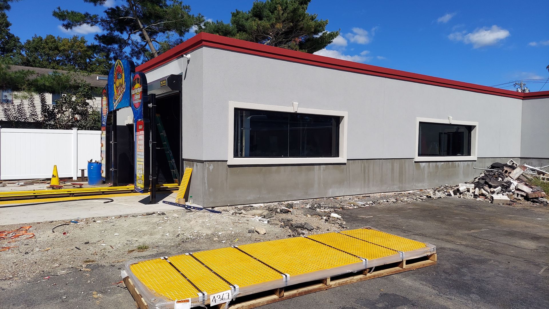 Portable modular building with white walls and red trim beside yellow ramps on a construction site