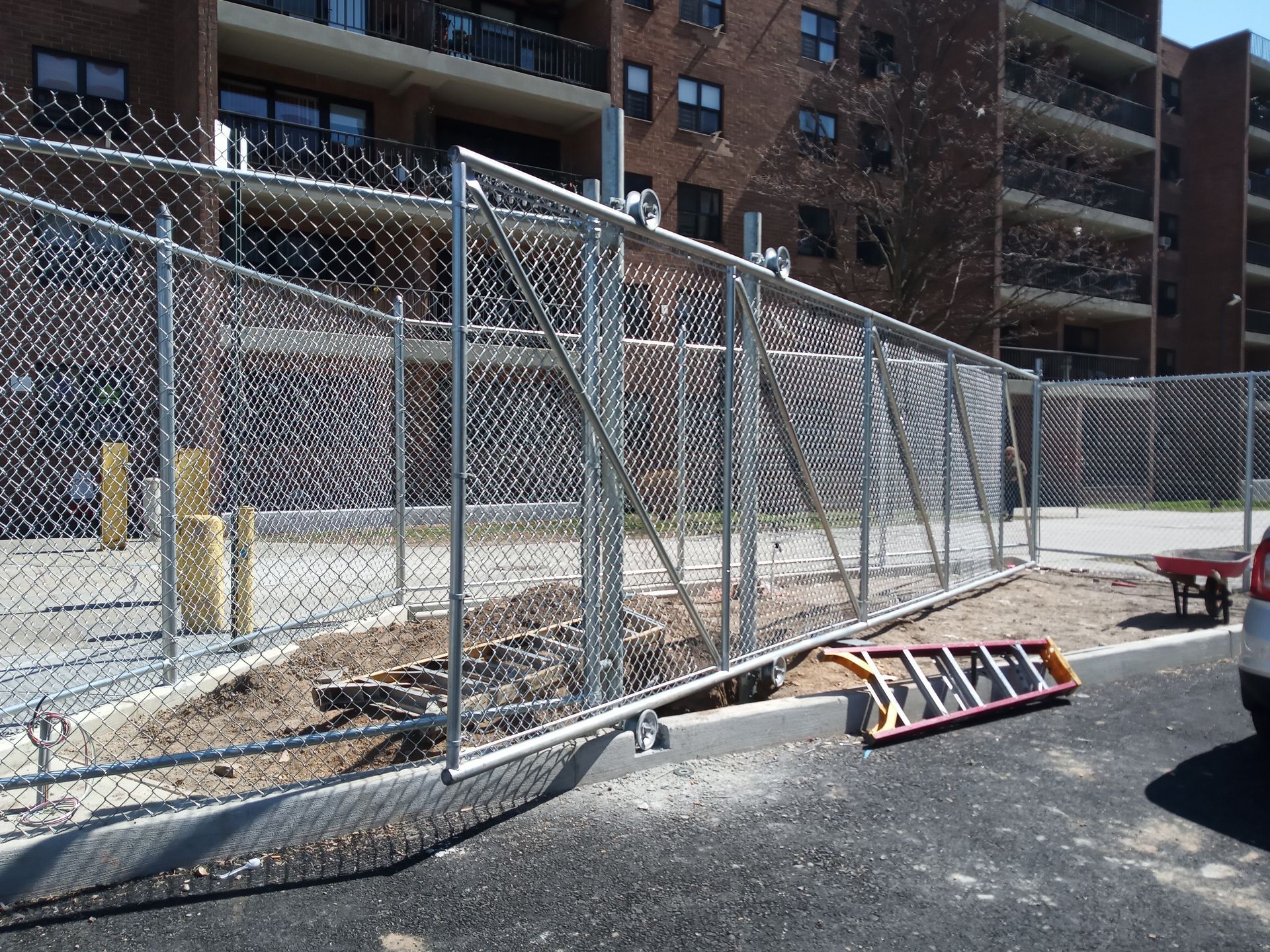 Construction fence and debris in a parking lot beside apartment buildings