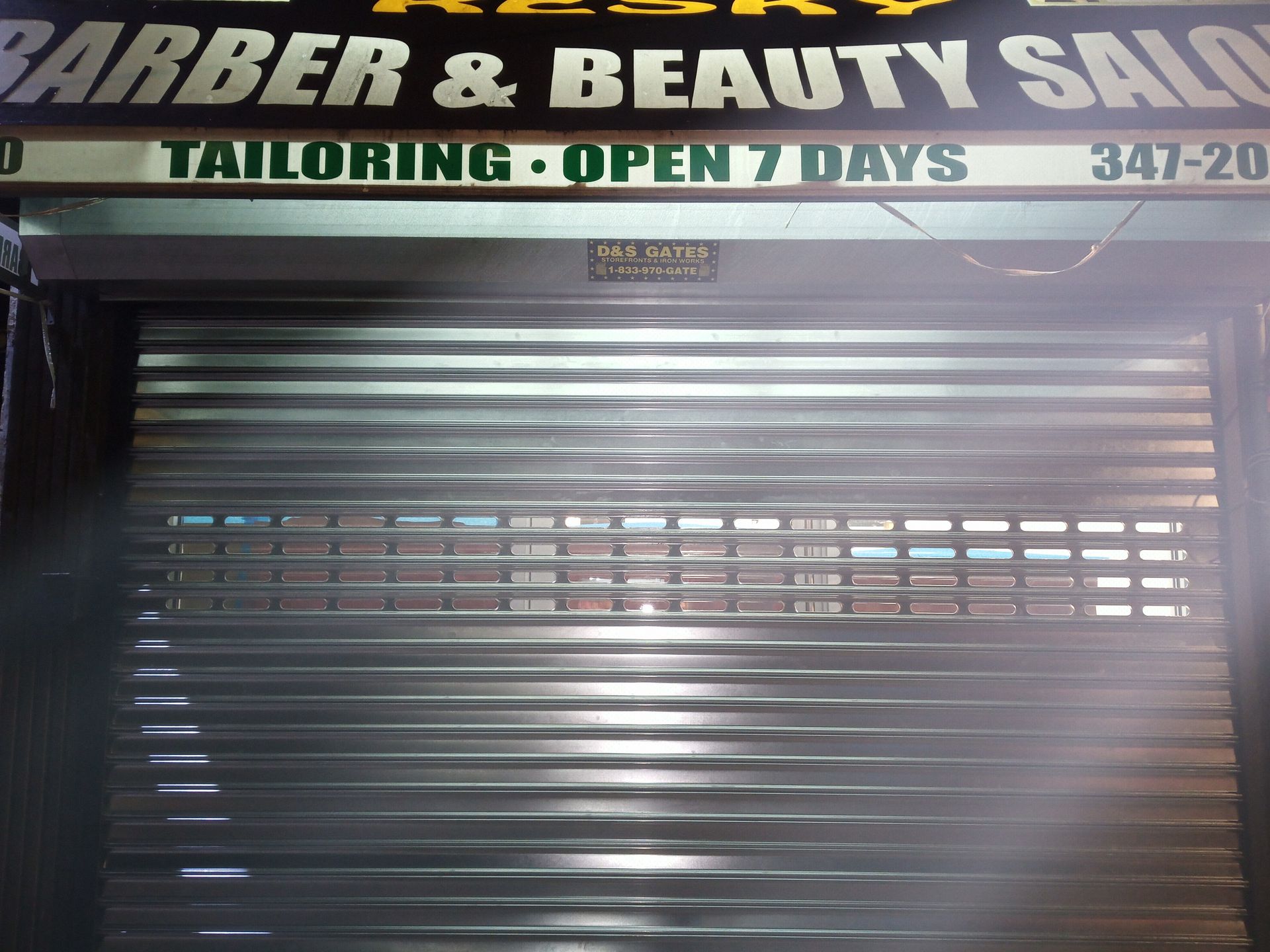 Closed barber and beauty salon storefront with metal shutter and sign overhead