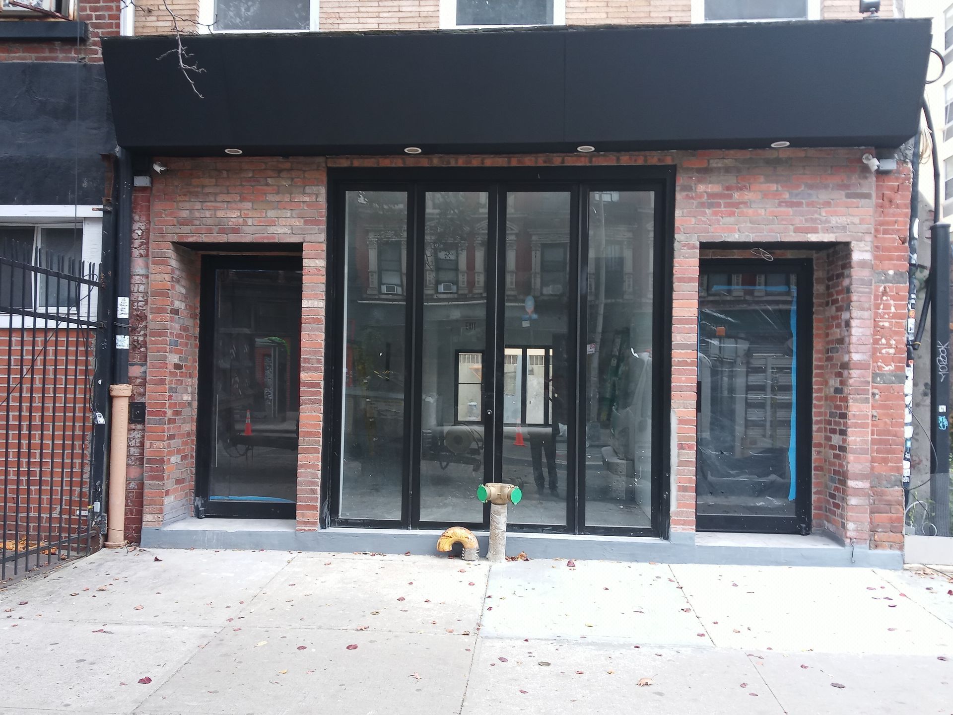 Brick storefront with black-framed glass doors and windows under a dark awning.