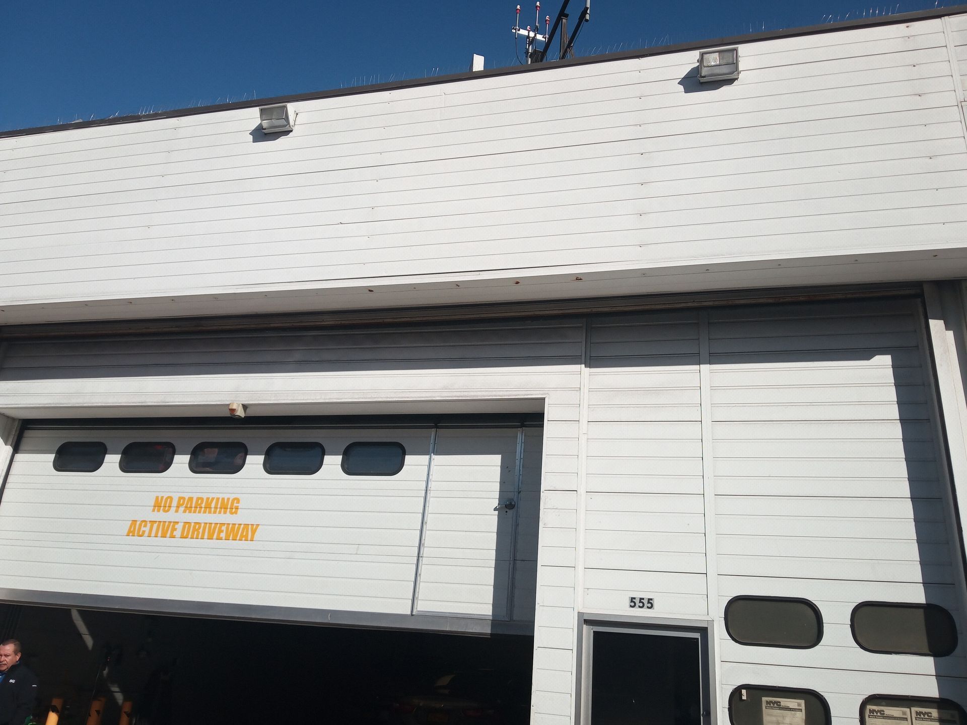 Garage door and building facade with a white panel exterior and yellow sign lettering.
