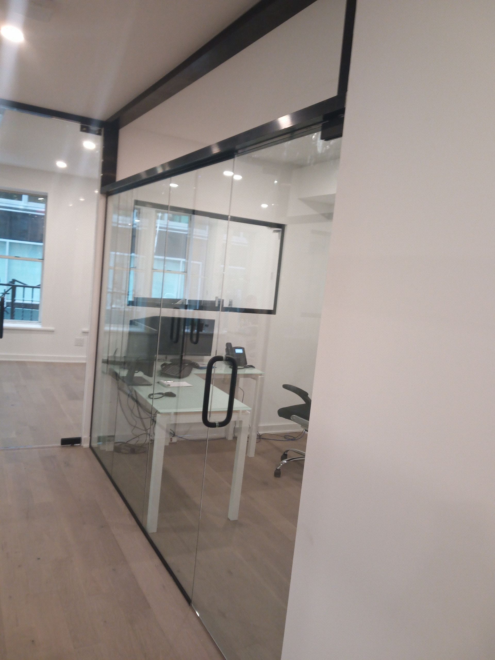 Modern office hallway with glass-walled meeting room and white walls