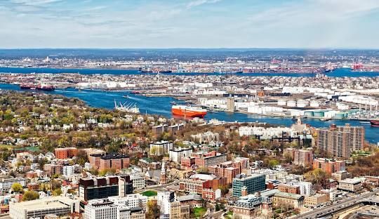 Aerial view of a coastal city with harbor, blue water, and dense buildings under a clear sky