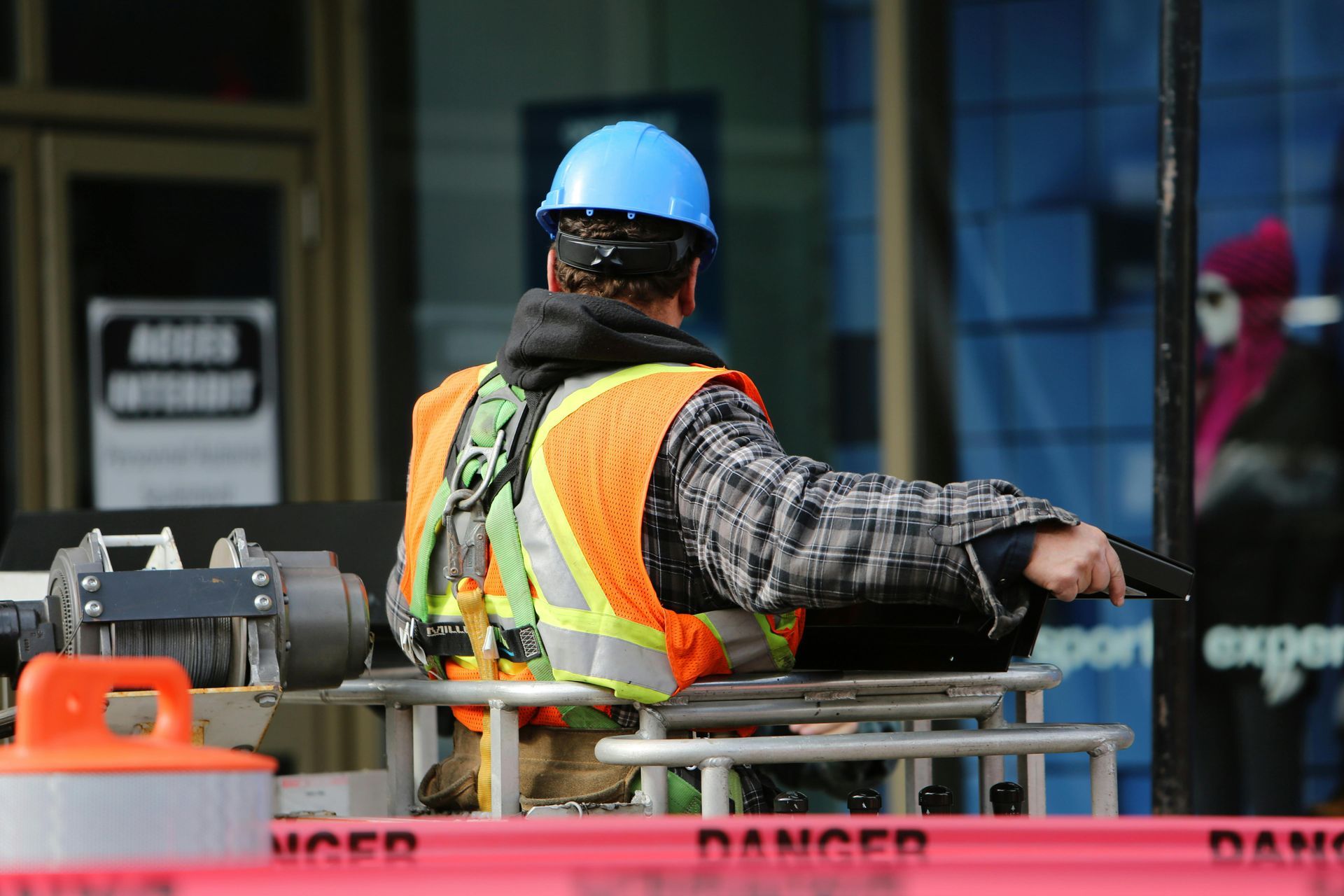 Construction worker in blue hard hat and orange vest directing traffic at a worksite