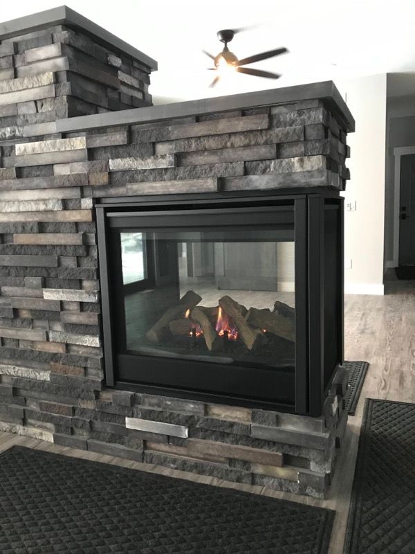 Stone fireplace with a glass-front gas insert and stacked gray brick surround in a modern living room