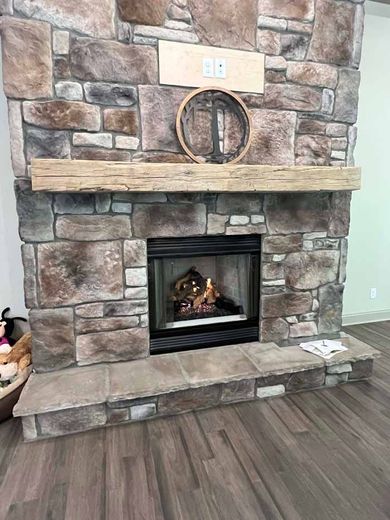 Modern wall-mounted electric fireplace with glowing logs beneath a mounted abstract artwork