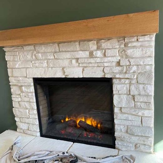 Stone fireplace with a glass-front gas insert and stacked gray brick surround in a modern living room