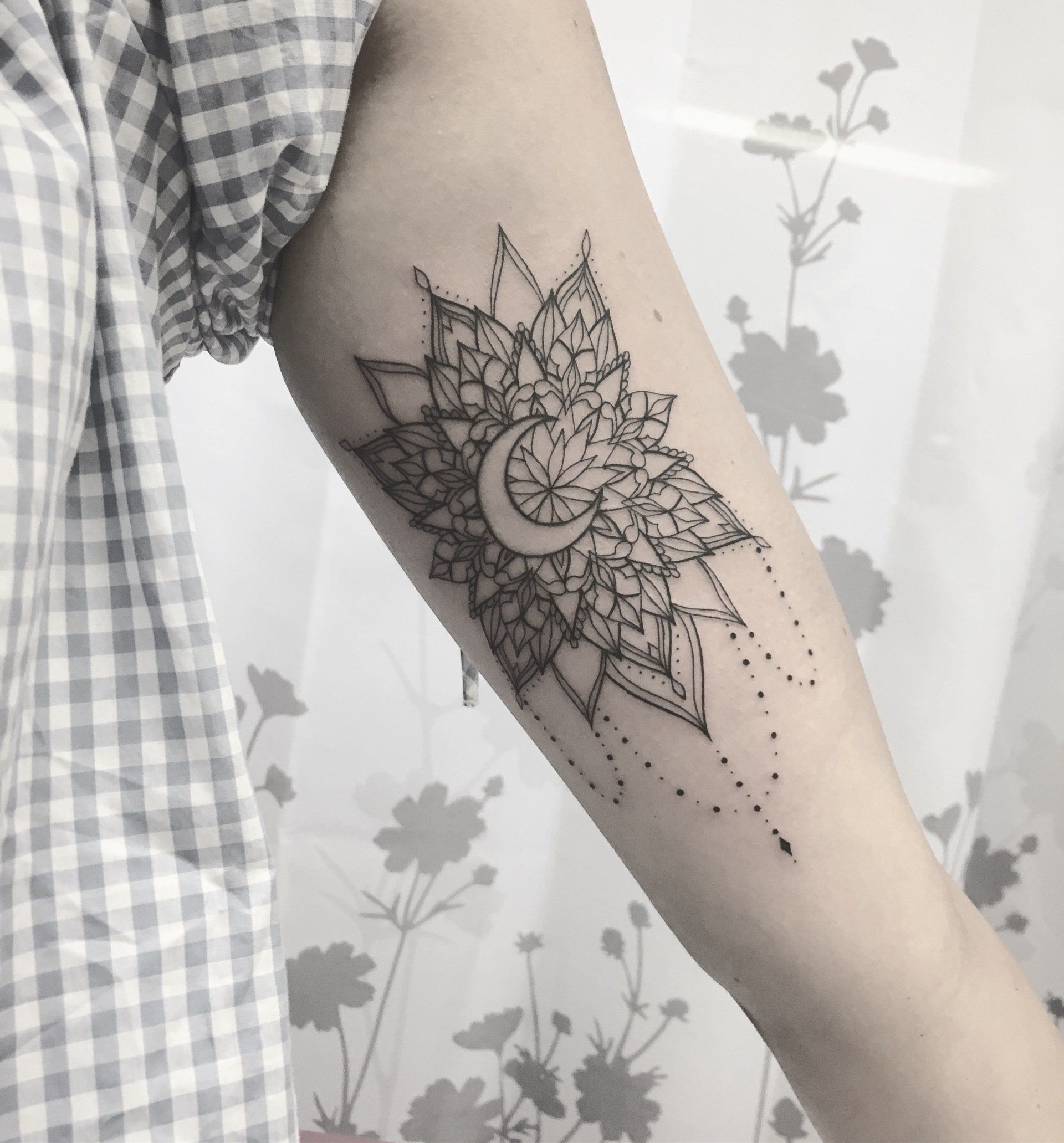 Schwarzes Mandala-Tattoo mit Halbmond auf dem Unterarm.