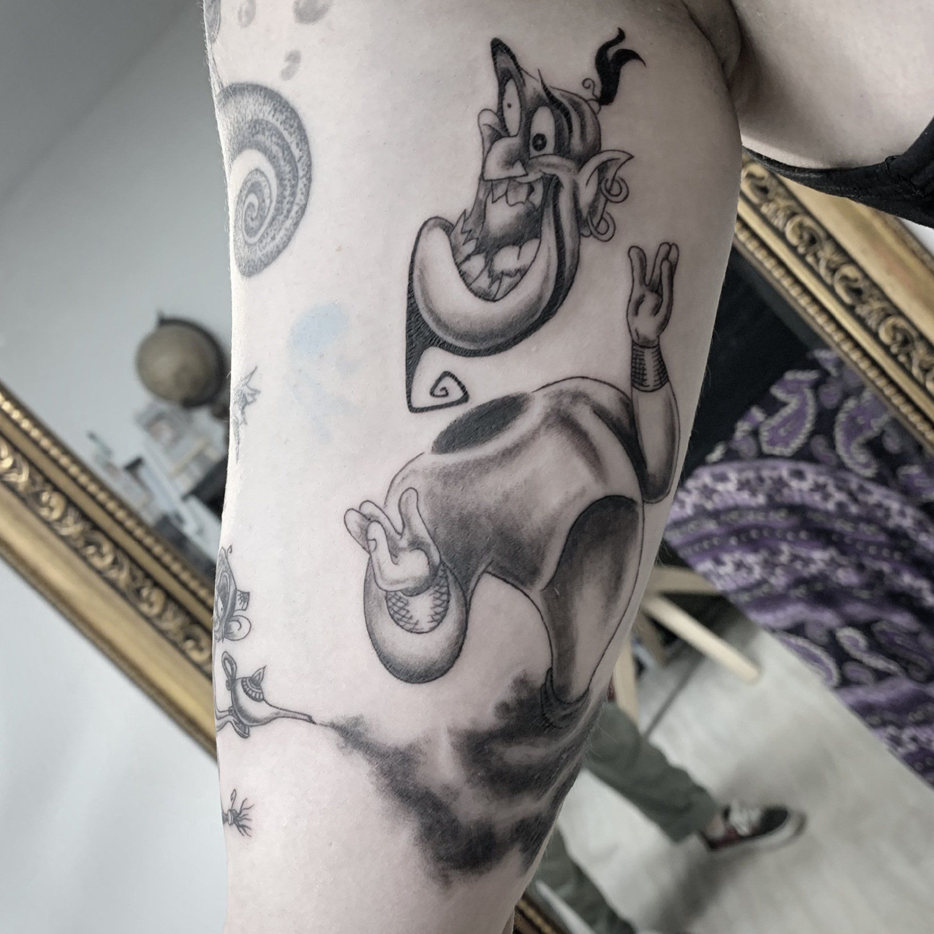 Schwarz-weißes Tattoo des Dschinns aus Aladdin; Oberkörper über einem rauchigen, schwebenden Unterkörper.