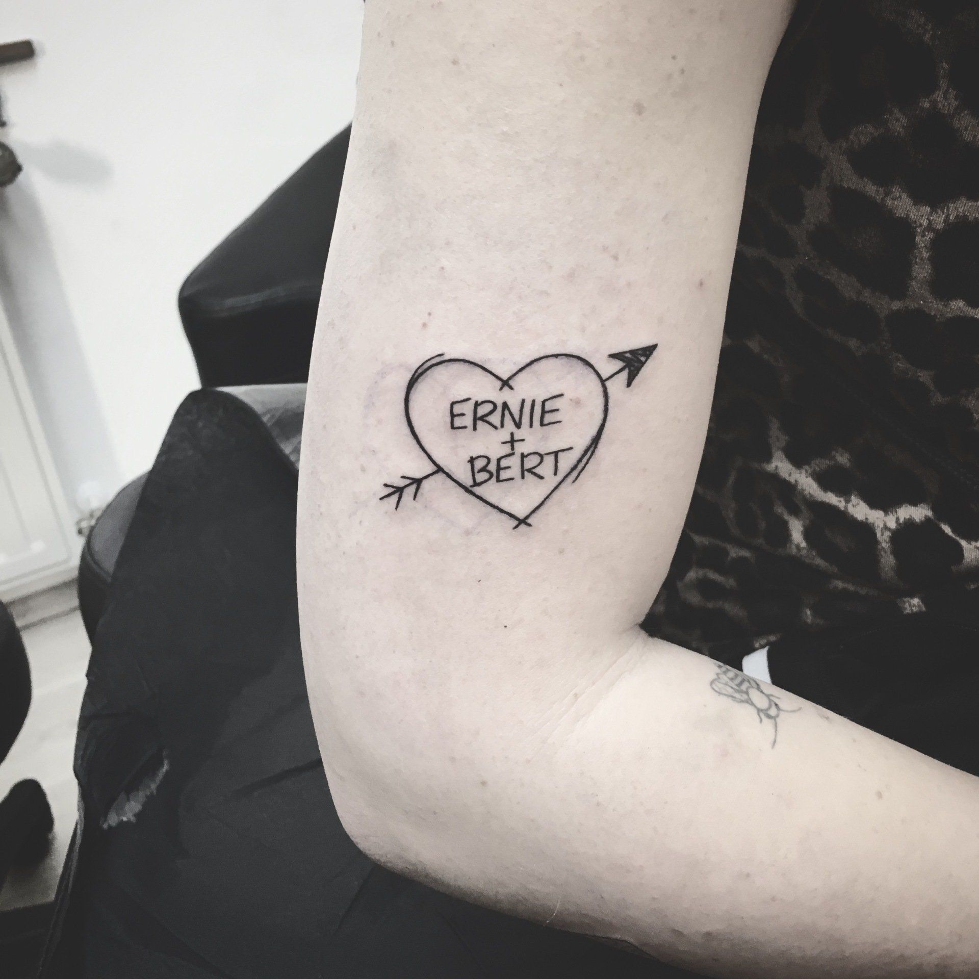 Tätowierung auf einem Arm: Herz mit der Aufschrift „ERNIE + BERT“, durchbohrt von einem Pfeil.