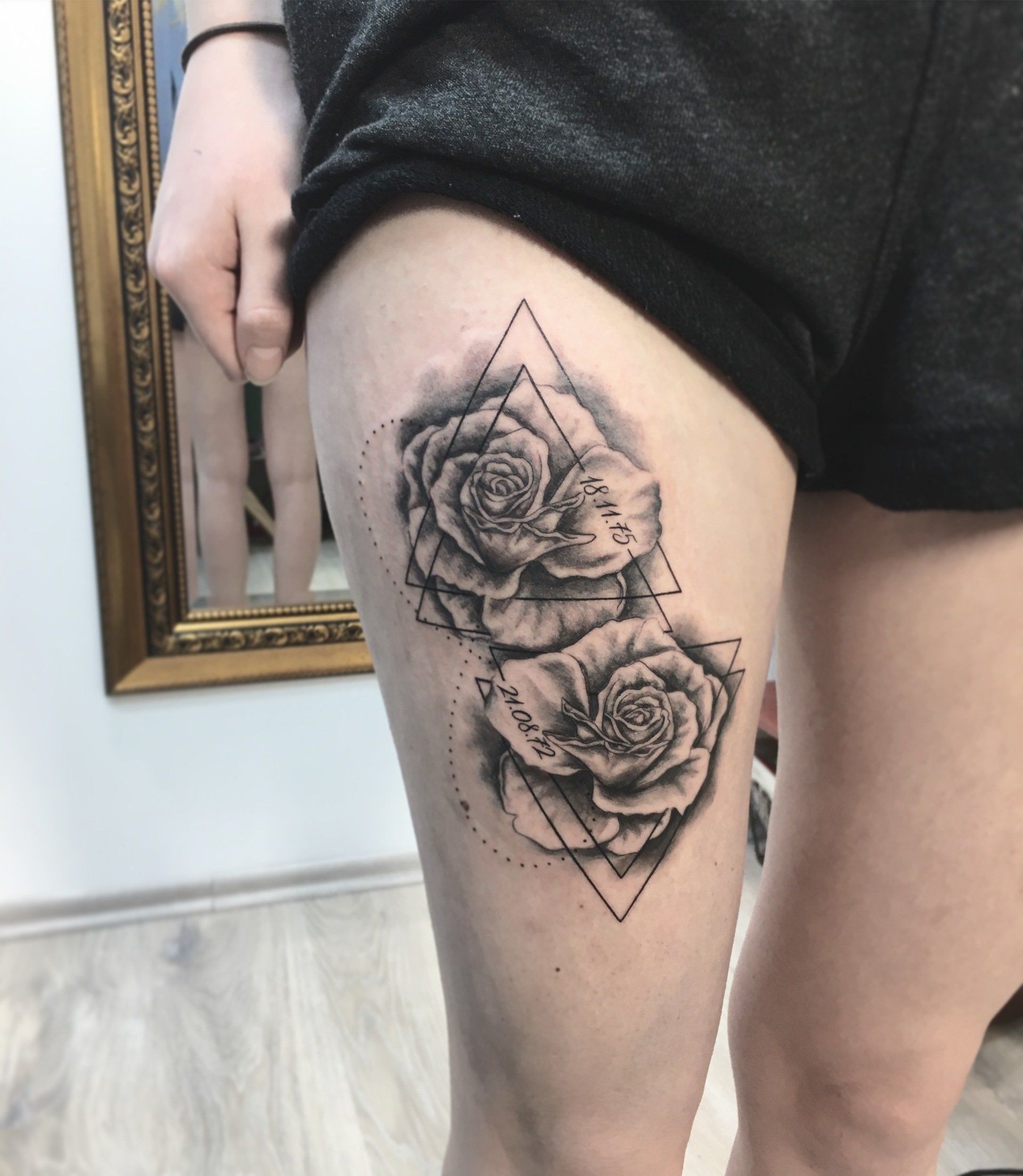 Tätowierung von zwei Rosen mit geometrischen Formen auf dem Oberschenkel einer Person.