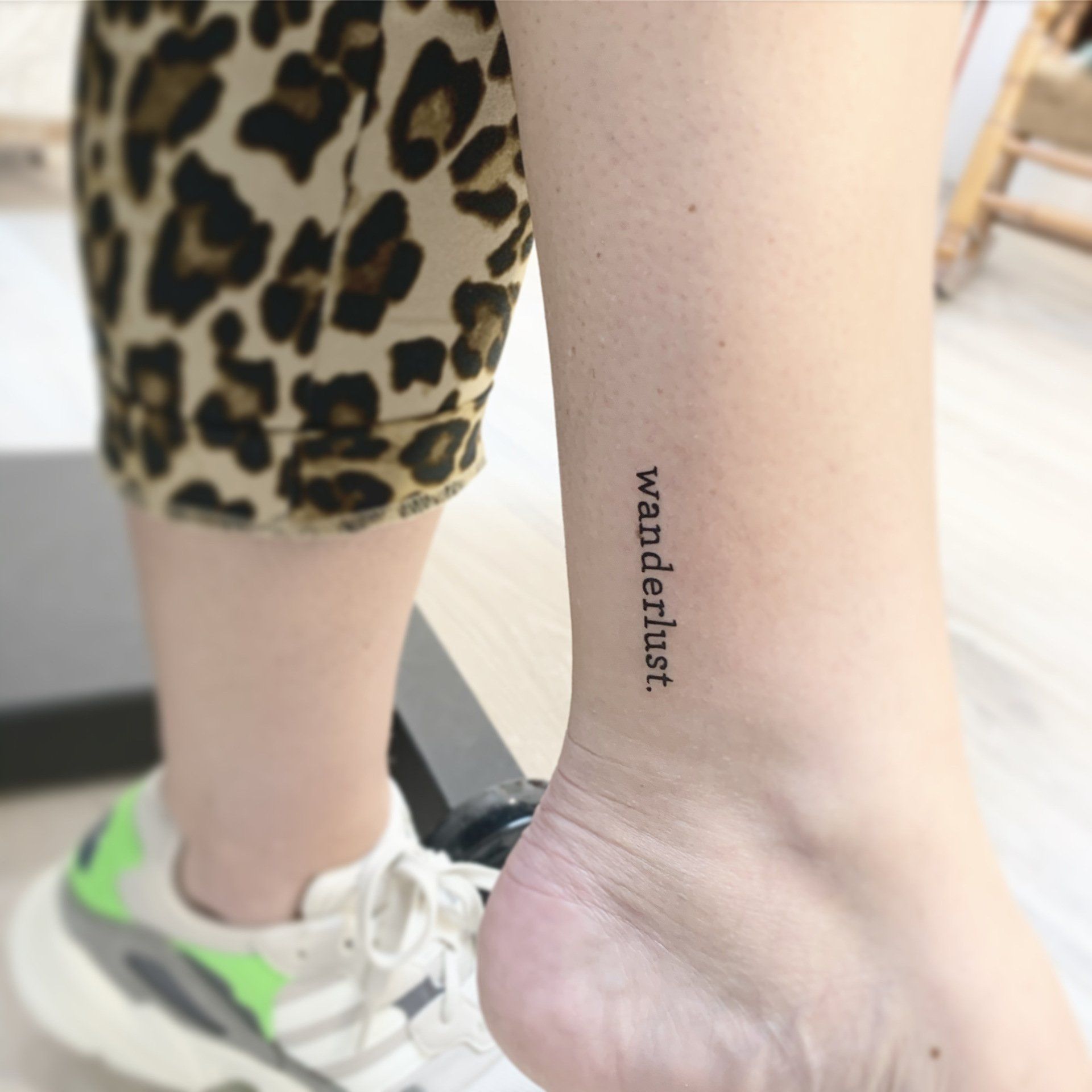 Tätowierung des Wortes „Fernweh“ senkrecht auf dem Knöchel einer Person, Nahaufnahme.