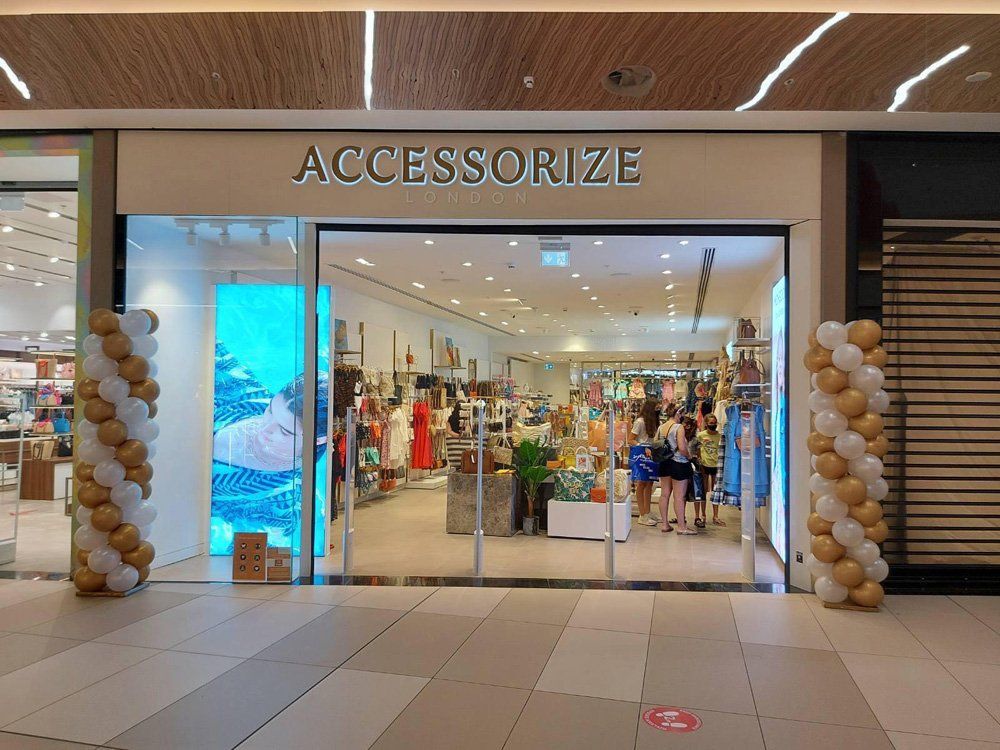AccessoriZE store entrance in a mall with balloon decorations and customers browsing.