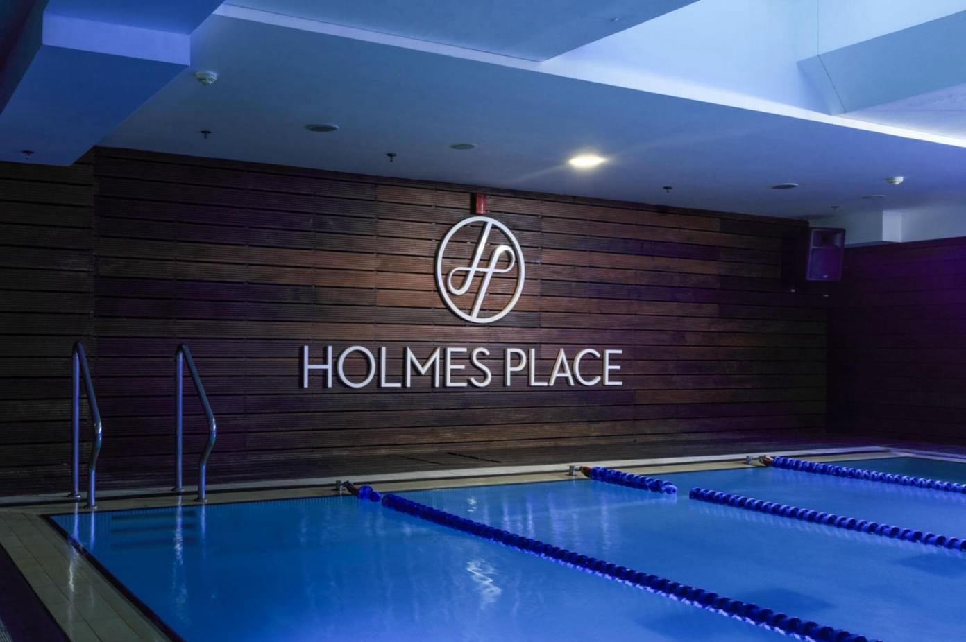 A swimming pool at Holmes Place gym, with the logo on a wooden wall.