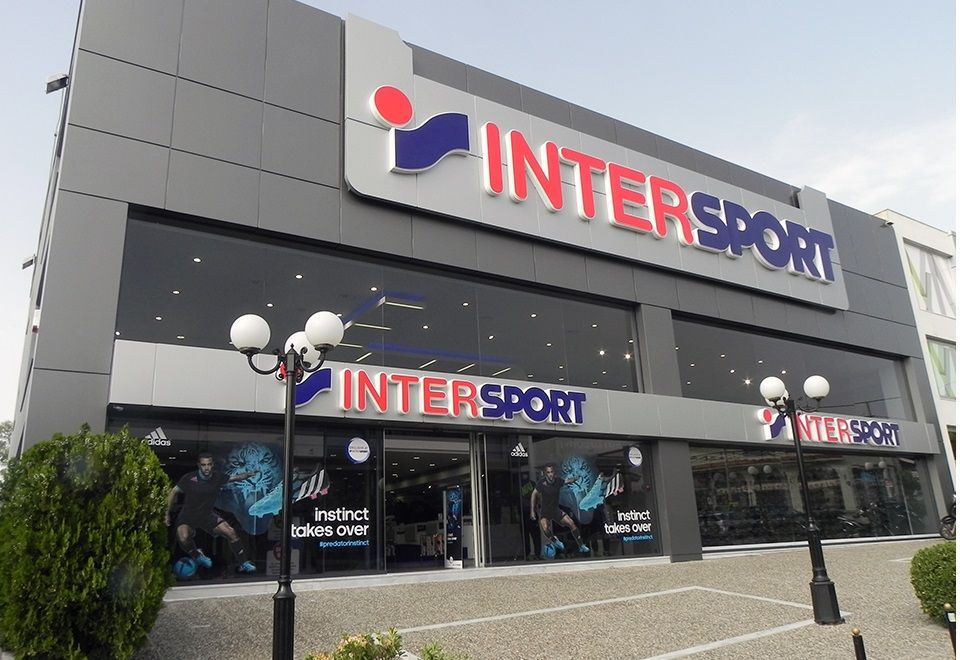 Exterior of an Intersport store with blue and red logo, large windows, and gray building.