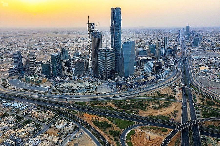 City skyline with modern skyscrapers in a desert setting, connected by highways at sunset.