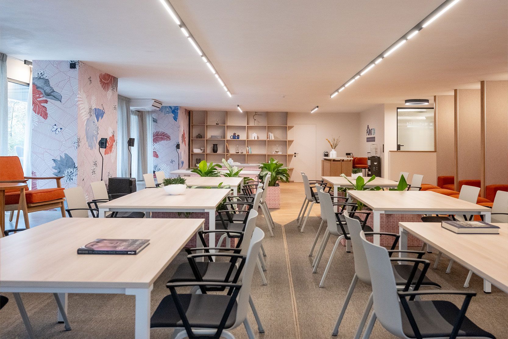 Modern office space with tables, chairs, and decorative wall.