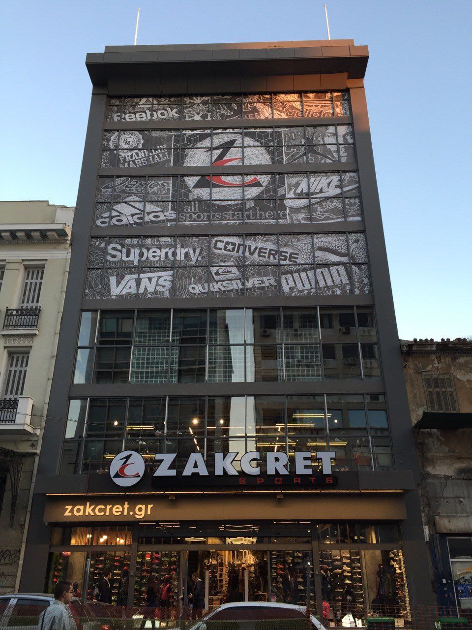 Zakcret shoe store in Athens, Greece, with logos of brands like Adidas, Superdry, and Vans on its facade.