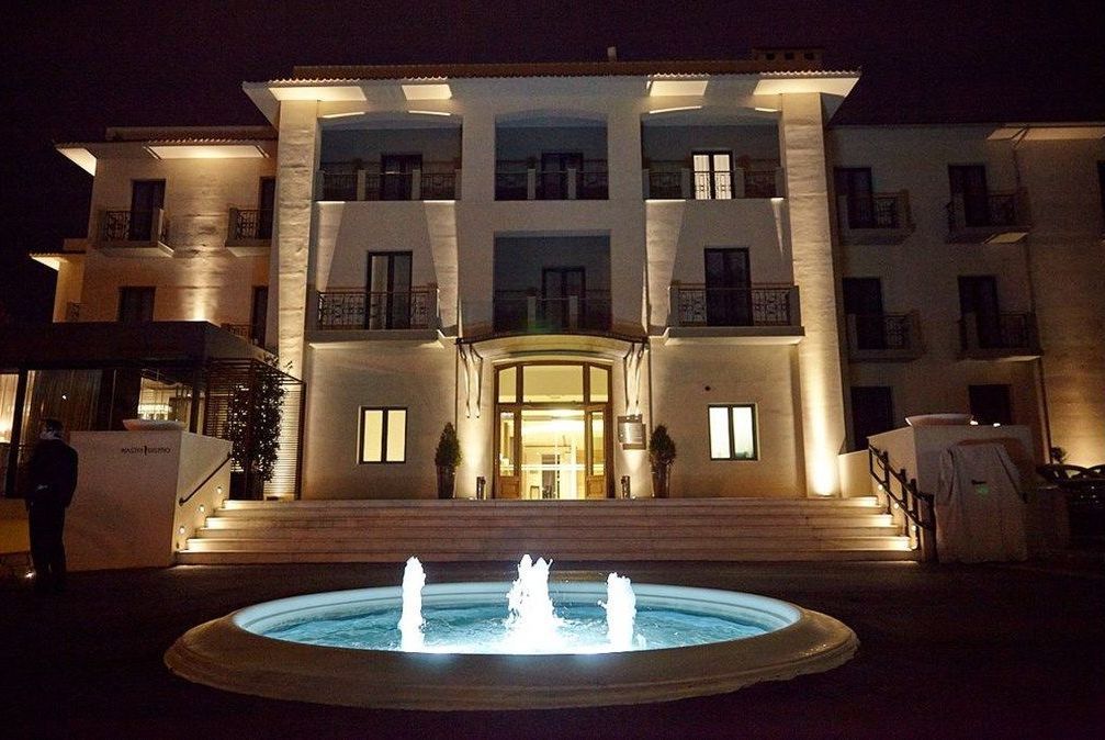 Hotel exterior at night, lit up. Features a fountain in front.