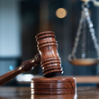 Martello da giudice in legno appoggiato su un blocco fonoassorbente in un'aula di tribunale.