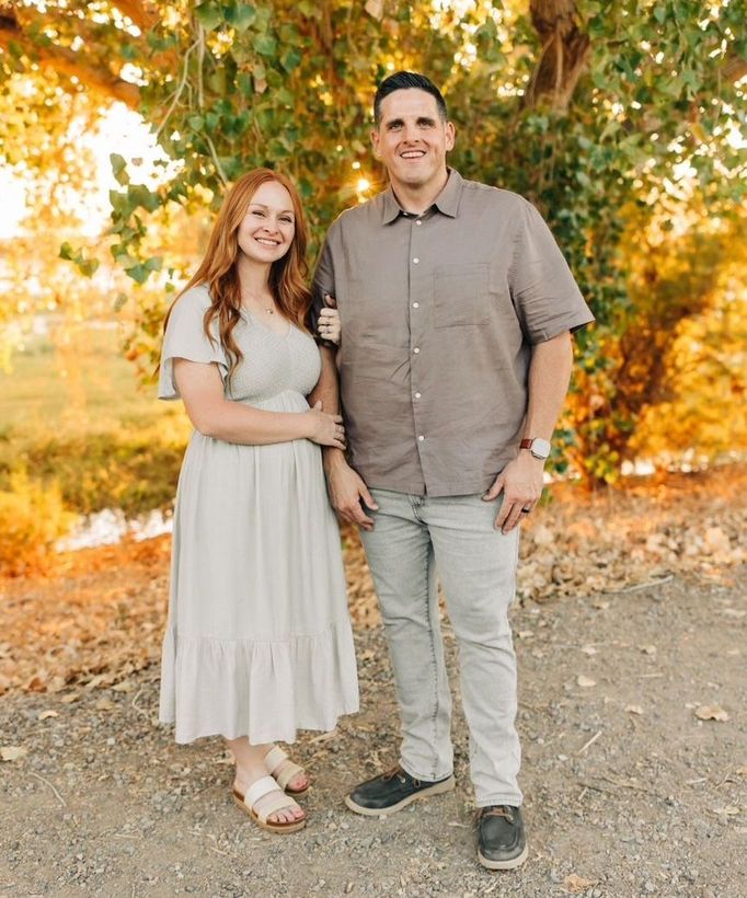 A man and a woman are standing next to each other under a tree.