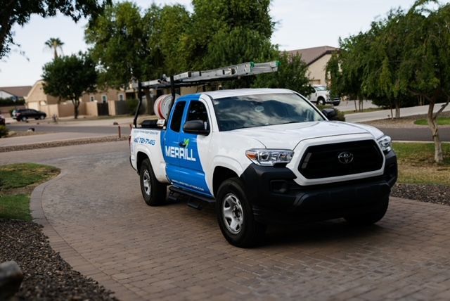 White-and-blue utility pickup truck parked on a residential street under trees