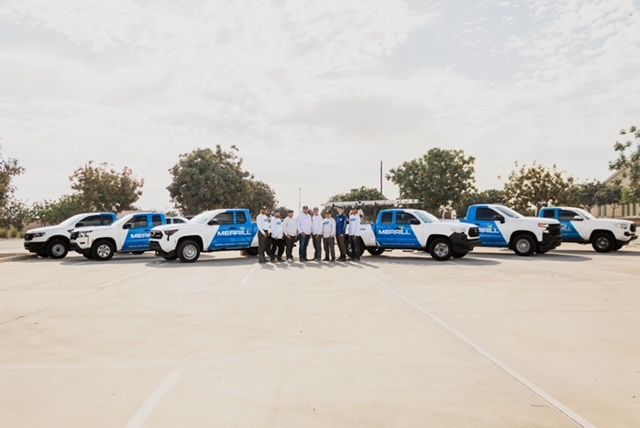 White-and-blue SUVs lined up with a group of people standing in the center on a large paved lot.