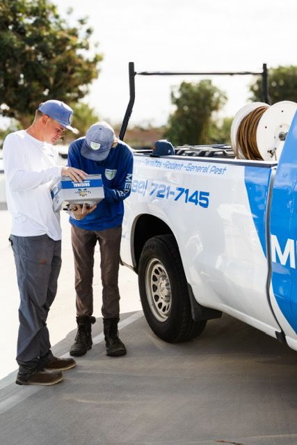 Two workers inspect papers beside a white-and-blue service truck outdoors
