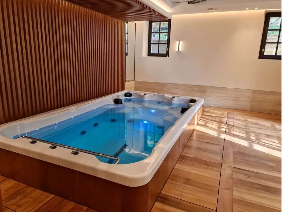 Une grande baignoire est installée dans une pièce avec un plancher en bois.