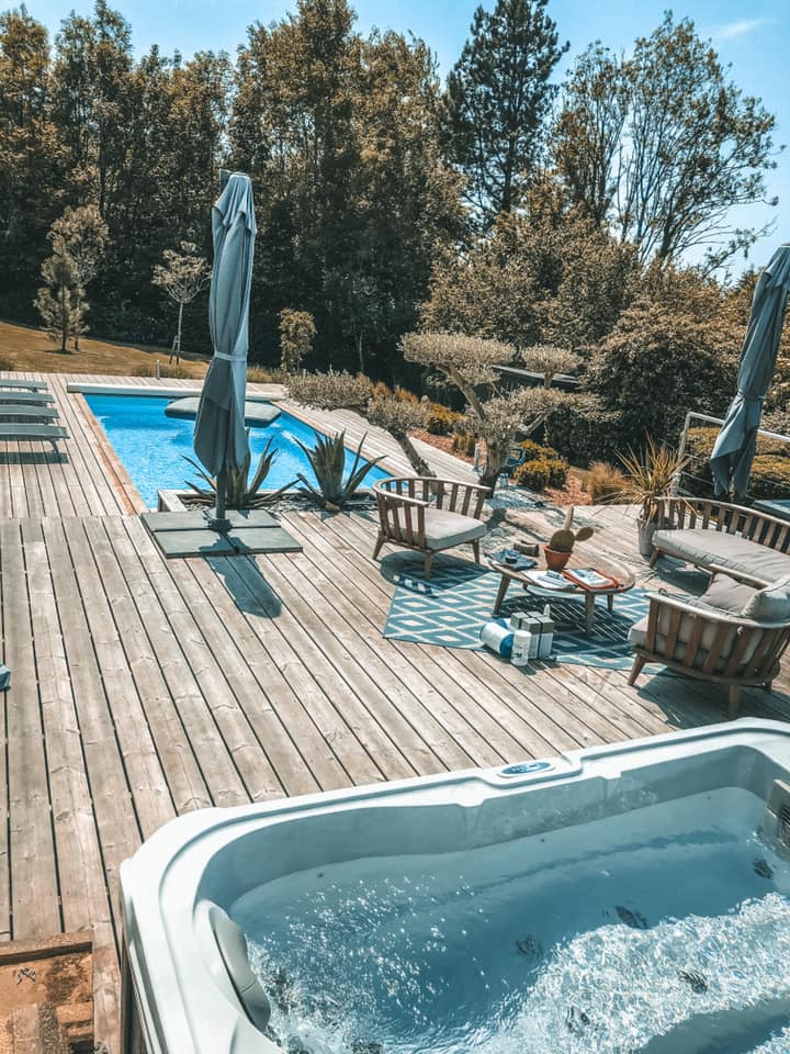 Un bain à remous est installé sur une terrasse en bois à côté d'une piscine.