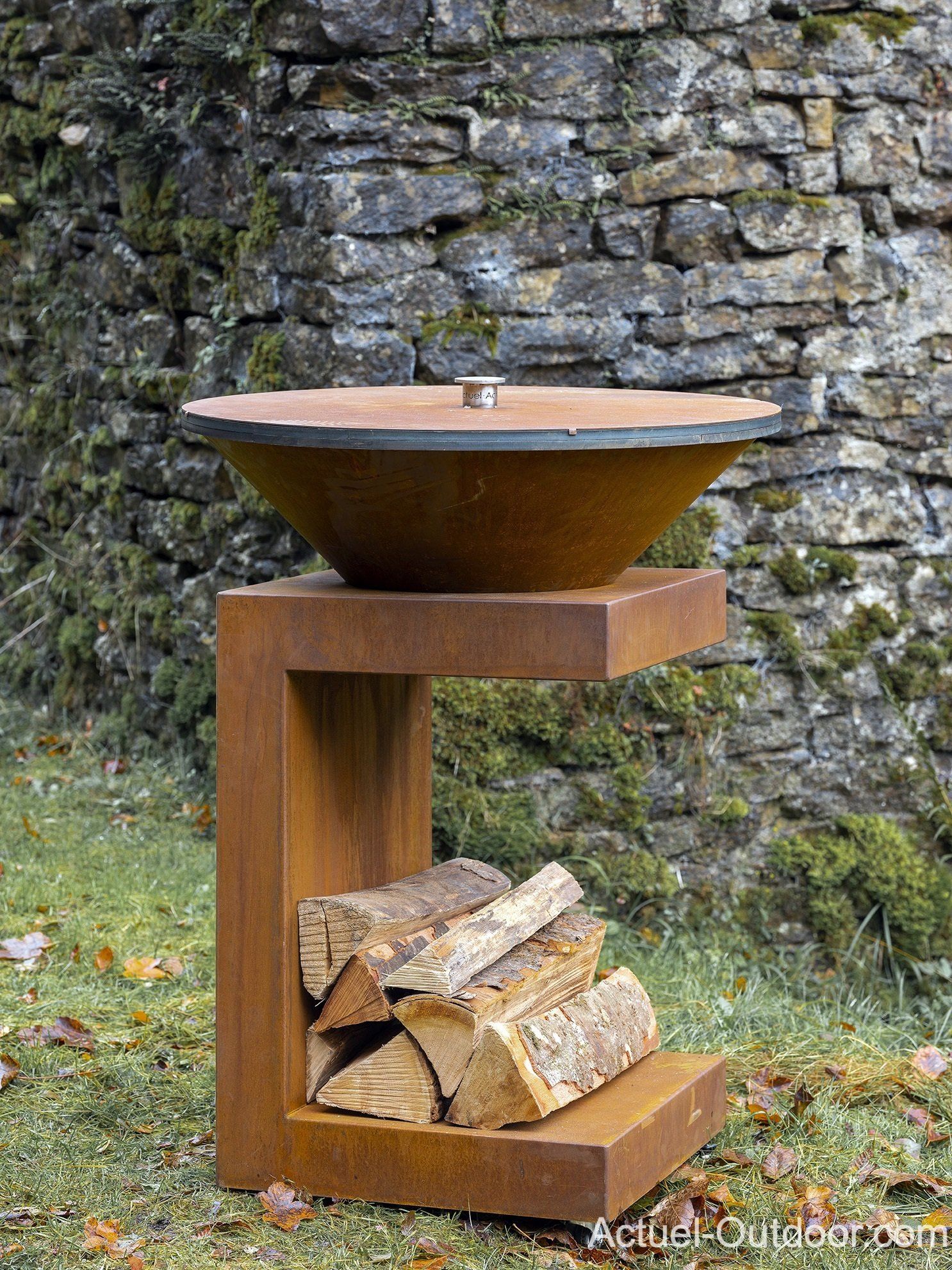 Une table en bois avec un bol et des bûches dessus devant un mur de pierre.