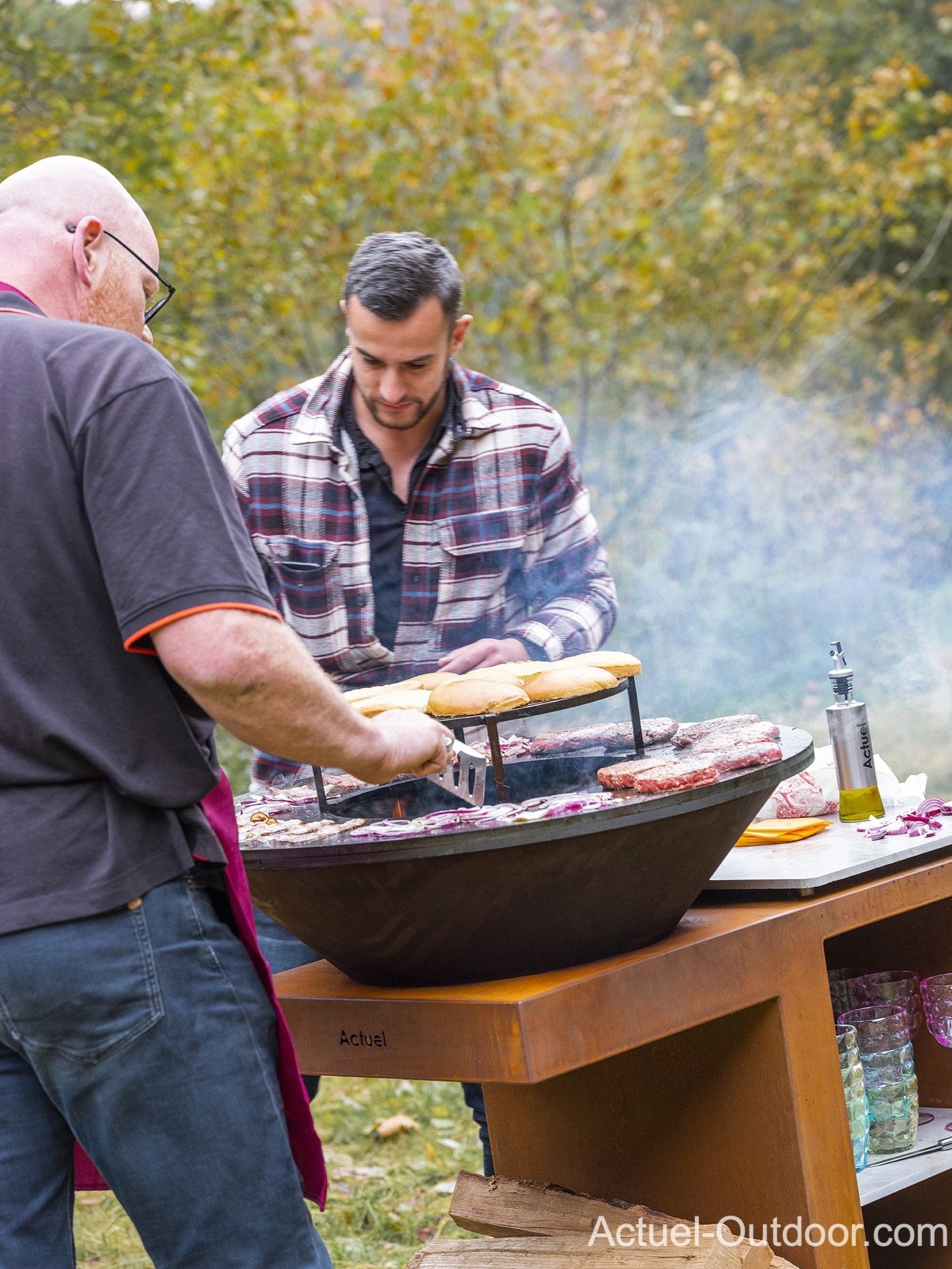 Deux hommes cuisinent de la nourriture sur un gril à l'extérieur.