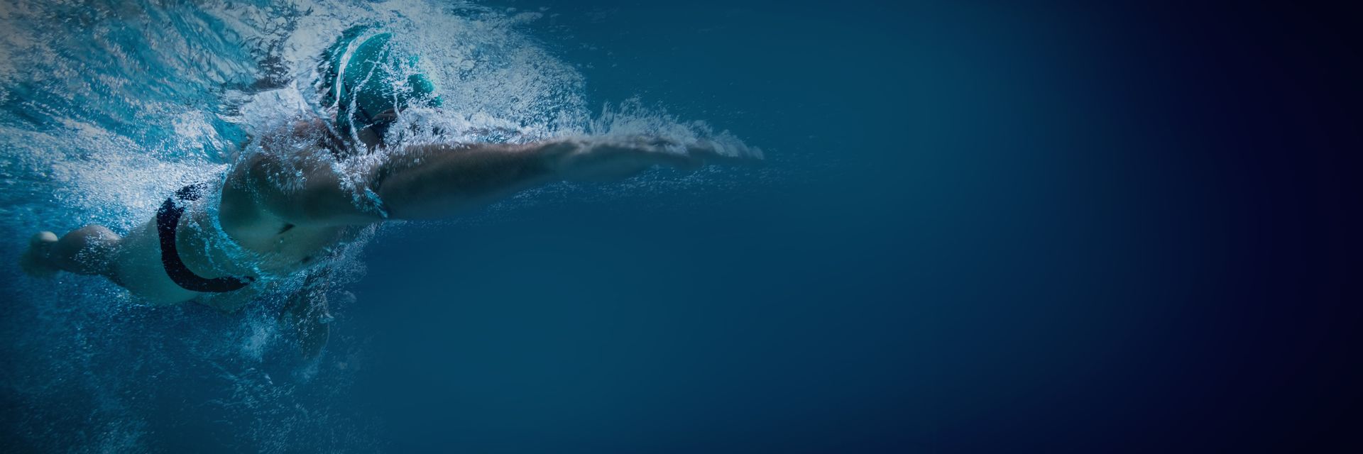 Une personne nage sous l'eau dans une piscine.