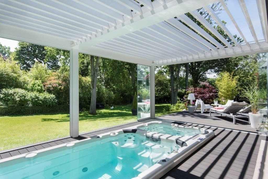 Une grande piscine est située sous une pergola dans une cour arrière.